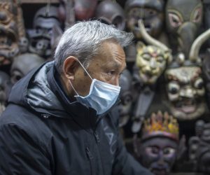 epa08175508 A vendor of traditional masks wears a facial mask at his shop in Thamel, a major tourist hub in Kathmandu, Nepal, 29 January 2020. Nepal's Health Ministry confirmed the first case of a coronavirus case in the country on 24 January 2020. Airports around the world are stepping up measures to stop the spreading of the novel coronavirus. Chinese authorities have urged people to stop travelling in and out of Wuhan, the city at the center of the new virus outbreak that has so far killed over 100 people and infected over thousands others, mostly in China.  EPA/NARENDRA SHRESTHA