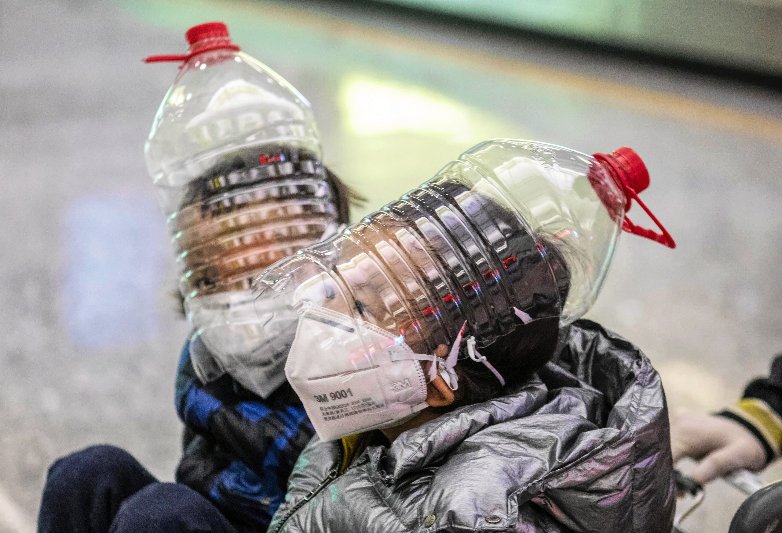 epa08185830 Childrean wear an improvised face protection made from water bottles in order to protect against the coronavirus at the airport arrival terminal in Guangzhou, Guangdong Province, China, 01 February 2020. Guangzhou Airport, usually busy during the end of Spring Festival when Chinese travelers return to their homes, appeared deserted after many countries and international airlines suspended or limited flights to and from China, because of outbreak of coronavirus in Wuhan City.  EPA/Alex Plavevski