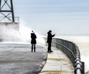 09 February 2020, Lower Saxony, Wilhelmshaven: Passers-by take pictures of the waves on a pier amid turbulent weather conditions due to storm Sabine. Photo: Hauke-Christian Dittrich/dpa