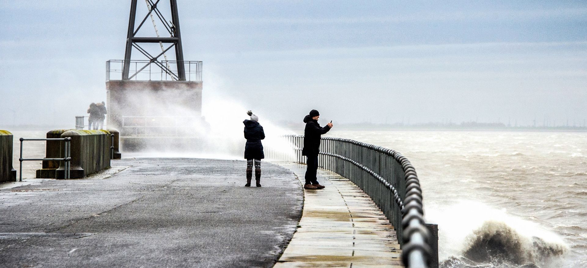 09 February 2020, Lower Saxony, Wilhelmshaven: Passers-by take pictures of the waves on a pier amid turbulent weather conditions due to storm Sabine. Photo: Hauke-Christian Dittrich/dpa