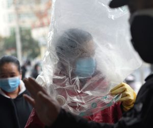 epa08208916 A masked shopper wearing a plastic bag is seen outside a supermarket in Wuhan, the epicenter of the novel coronavirus outbreak, in central China's Hubei province, 10 February 2020.  EPA/SHEPHERD ZHOU CHINA OUT
