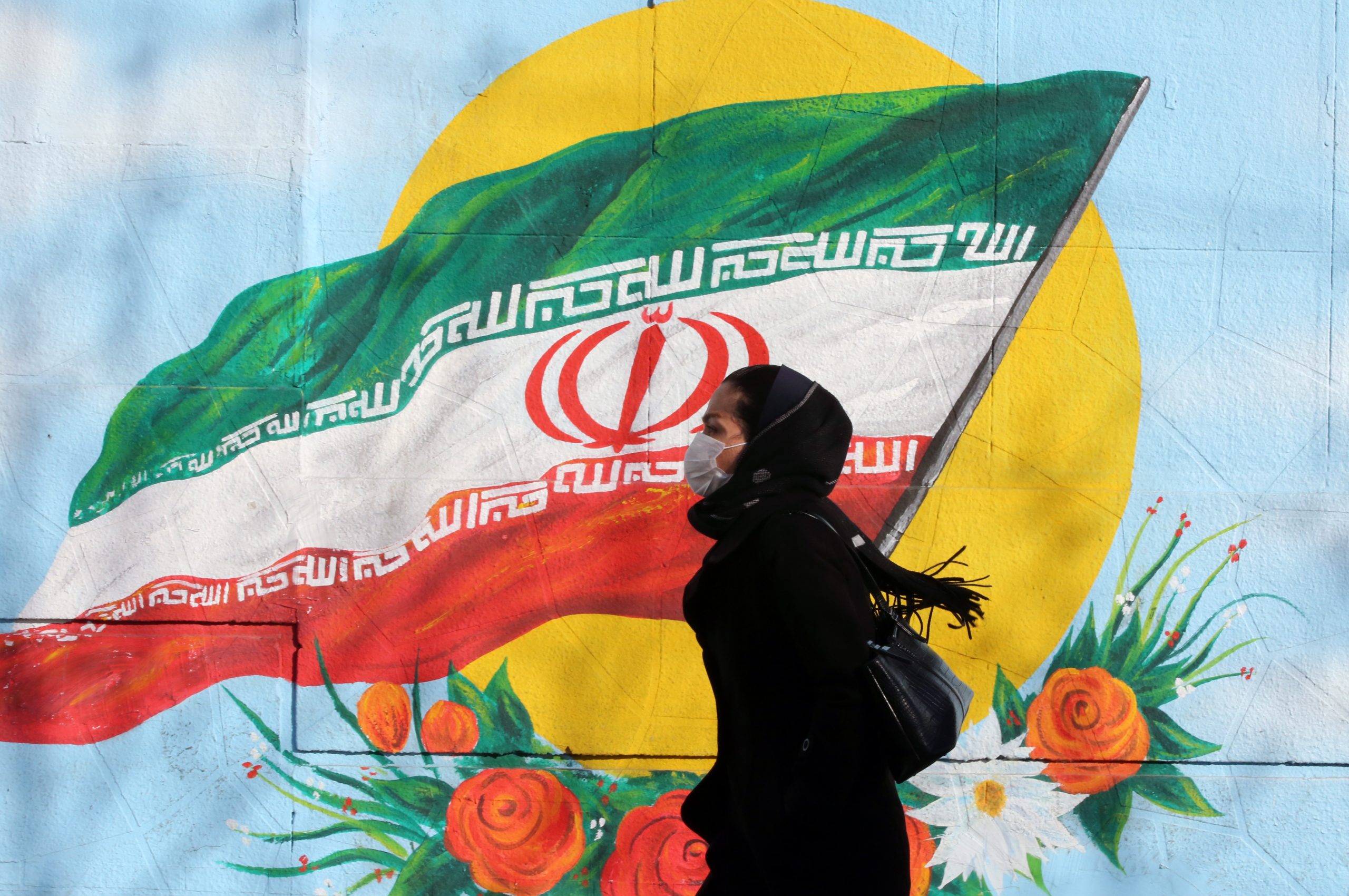 epa08228565 (FILE) - An Iranian woman wearing a mask walks next to a wall painting of Iranian national flag in Tehran, Iran, 12 February 2020 (reissued 19 February 2020). According to the Ministry of Health, two people diagnosed with coronavirus died in the city of Qom, central Iran.  EPA/ABEDIN TAHERKENAREH