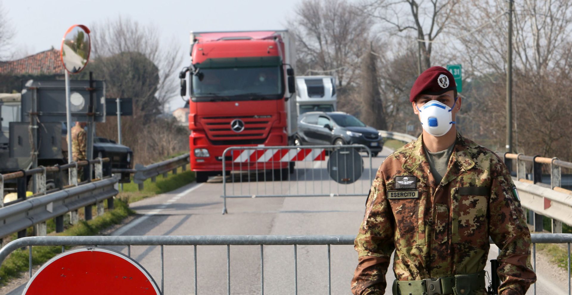epa08244050 An Italian Army officer wearing a protective face mask stands at a roadblock at the entrance to the small town of Vo' Euganeo, near Padova, northern Italy, 24 February 2020. Italian authorities announced on the day that there are over 200 confirmed cases of COVID-19 disease in the country, with at least five deaths. Precautionary measures and ordinances to tackle the spreading of the deadly virus included the closure of schools, gyms, museums and cinemas in the affected areas in northern Italy.