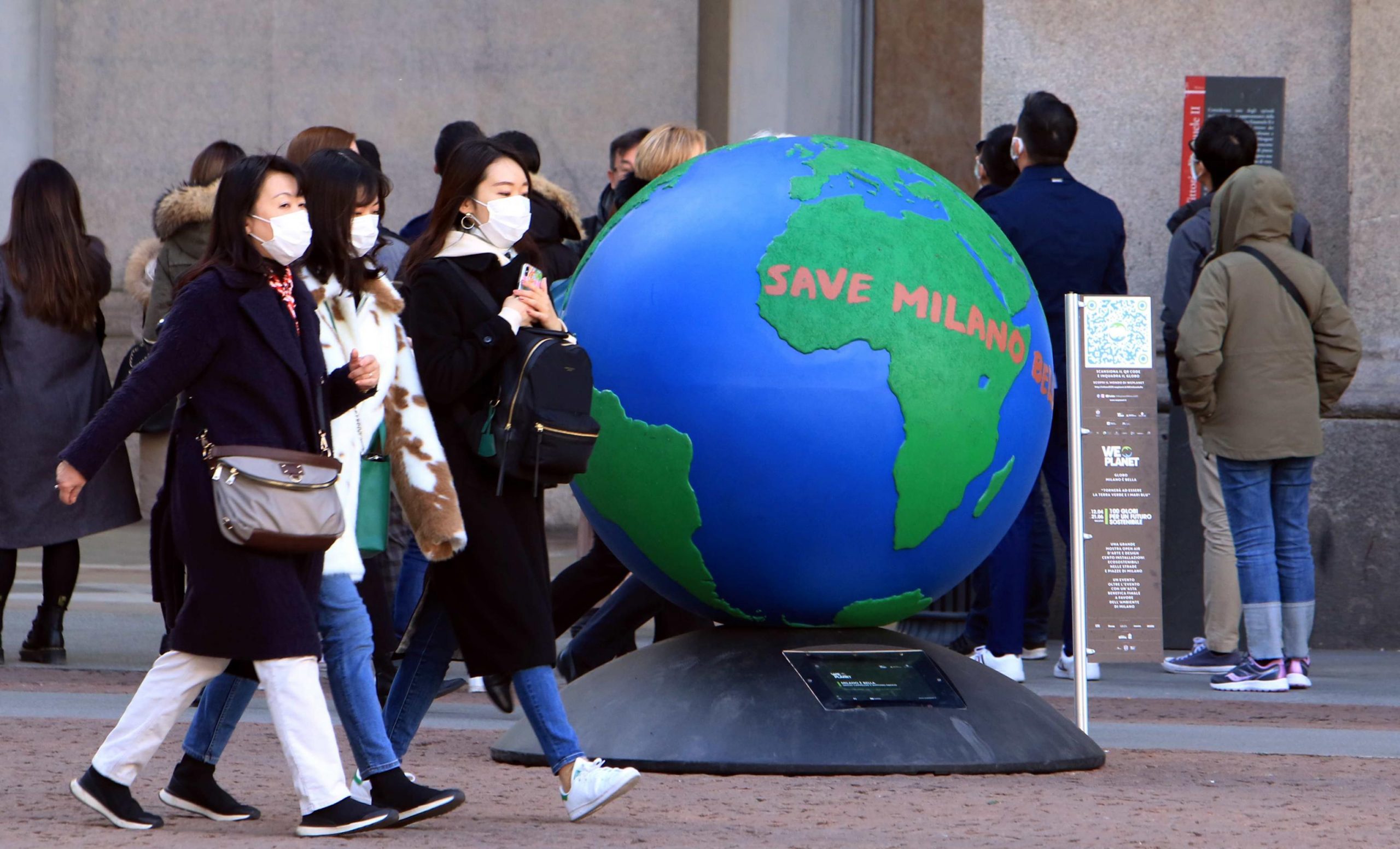 epa08253076 Asian tourists wearing protective mask walk next the istallation 'We planet', a part of hundred globes scattered around the city center made by artists asking for a sustainable future, Milan, Italy, 27 February 2020. Officials say that the number of people which have died due to the COVID-19 coronavirus in Italy has climbed to 12 while more than 400 persons have contracted the virus.  EPA/Paolo Salmoirago