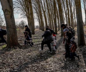 epa08262374 A group of migrants with children walks into a wood near the Meric (Evros) River at the Turkish-Greek border, in Edirne, Turkey, 01 March 2020. Thousands of refugees and migrants are gathering on the Turkish side of the border with Greece with the intent to cross into the European Union following the Turkish government's decision to loosen controls on migrant flows after the death of 33 Turkish soldiers killed in an attack in Idlib, Syria on 27 February.  EPA/SEDAT SUNA