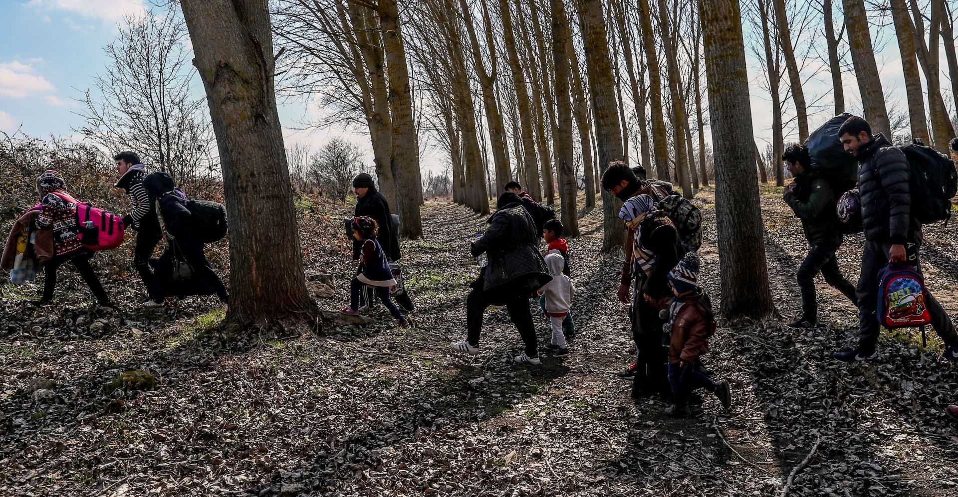 epa08262374 A group of migrants with children walks into a wood near the Meric (Evros) River at the Turkish-Greek border, in Edirne, Turkey, 01 March 2020. Thousands of refugees and migrants are gathering on the Turkish side of the border with Greece with the intent to cross into the European Union following the Turkish government's decision to loosen controls on migrant flows after the death of 33 Turkish soldiers killed in an attack in Idlib, Syria on 27 February.  EPA/SEDAT SUNA