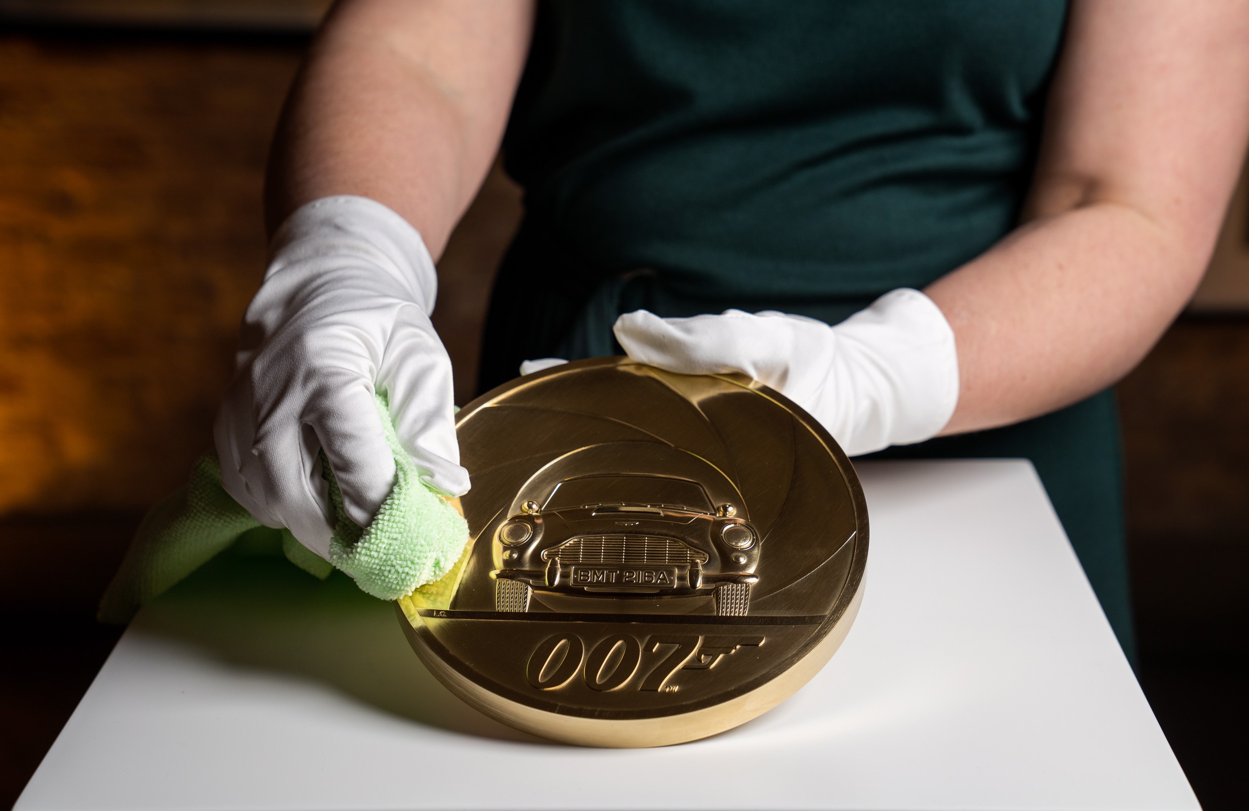 epa08266251 An undated handout photo made available by the British Royal Mint in London, Britain shows Laura Clancy (out of frame), designer at The Royal Mint, displaying a special edition James Bond themed seven-kilogram Gold Proof coin (issued 03 March 2020). The coin was unveiled on 02 March 2020, alongside a wider James Bond commemorative coin and gold bar collection at a launch event at Bond in Motion, Covent Garden, to celebrate the upcoming release of the 25th James Bond film.  EPA/THE ROYAL MINT HANDOUT  HANDOUT EDITORIAL USE ONLY/NO SALES
