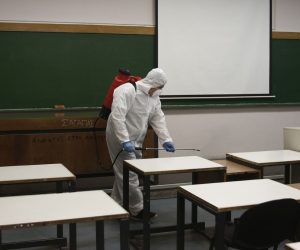 epa08293107 A worker wearing protective gear sprays disinfectant inside a classroom as a precaution against the spread of the Covid-19 Coronavirus, at the Polytechnic University in Athens, Greece, 13 March 2020. Greece's museums and archaeological sites will also be suspending their operation until March 30 due to a shortage of staff, the culture ministry announced on Friday. With 117 cases, Greece on Friday ranked 25th in the list of countries with confirmed SARS-CoV-2 virus cases.  EPA/YANNIS KOLESIDIS
