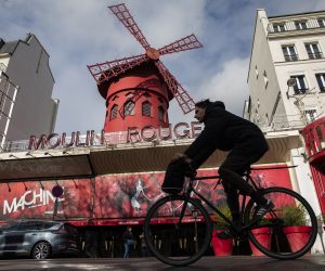 epa08294517 A man cycles past the Moulin Rouge cabaret which closed as part of measures to contain the spread of coronavirus SARS-CoV-2 which causes the Covid-19 disease, in Paris, France, 14 March 2020. France will ban all gatherings of more than 100 people due to the coronavirus pandemic, French Prime Minister Philippe announced on 13 March 2020. President Macron announced the closing of schools, high schools and nurseries from 16 March 2020 on. Over 3,660 cases of COVID-19 infections and 79 deaths have been confirmed so far in France, reports state.  EPA/IAN LANGSDON