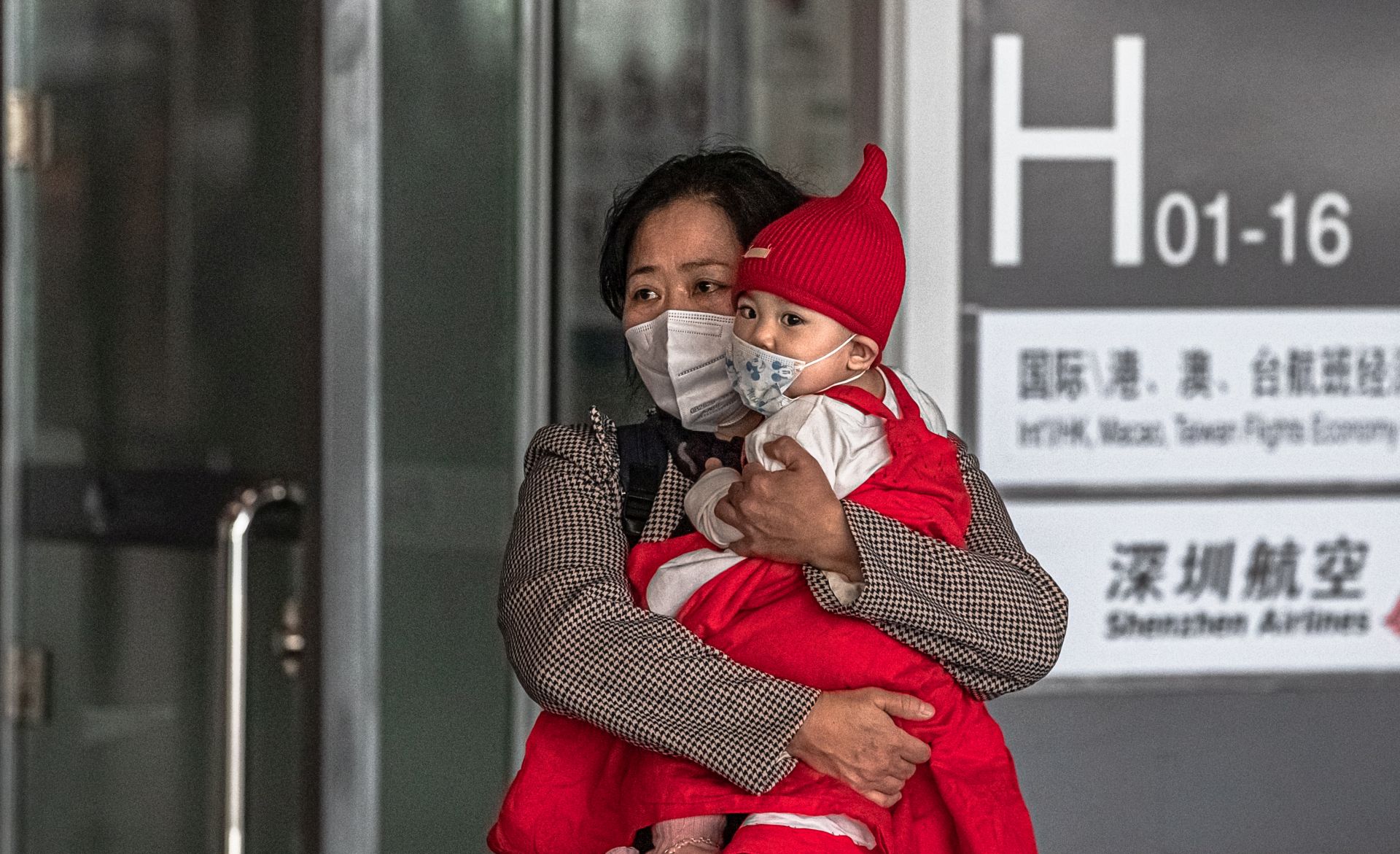epa08300650 A woman carries a child wearing a protective face mask at the Capital International Airport, in Beijing, China, 17 March 2020. According to media reports, Beijing enforced a 14-day quarantine on international travellers arriving in China's capital. All passengers arriving from abroad go through the screening at the transfer center from where most of them are transferred in designated quarantine facilities.  EPA/ROMAN PILIPEY