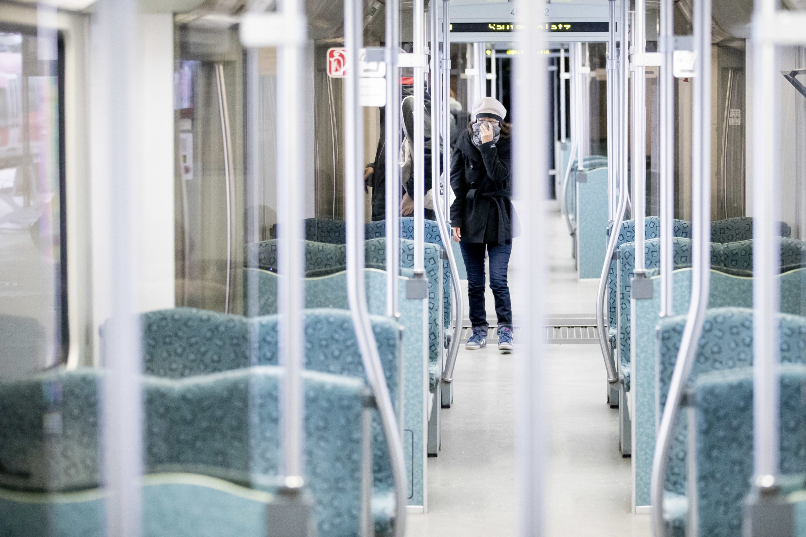 20 March 2020, Berlin: A woman holds her scarf in front of her mouth as she walks on an almost deserted suburban train. Germany has introduced drastic restrictions on public life and strict travel bans as part of efforts to curb the spread of the Coronavirus (SARS-CoV-2). Photo: Christoph Soeder/dpa
