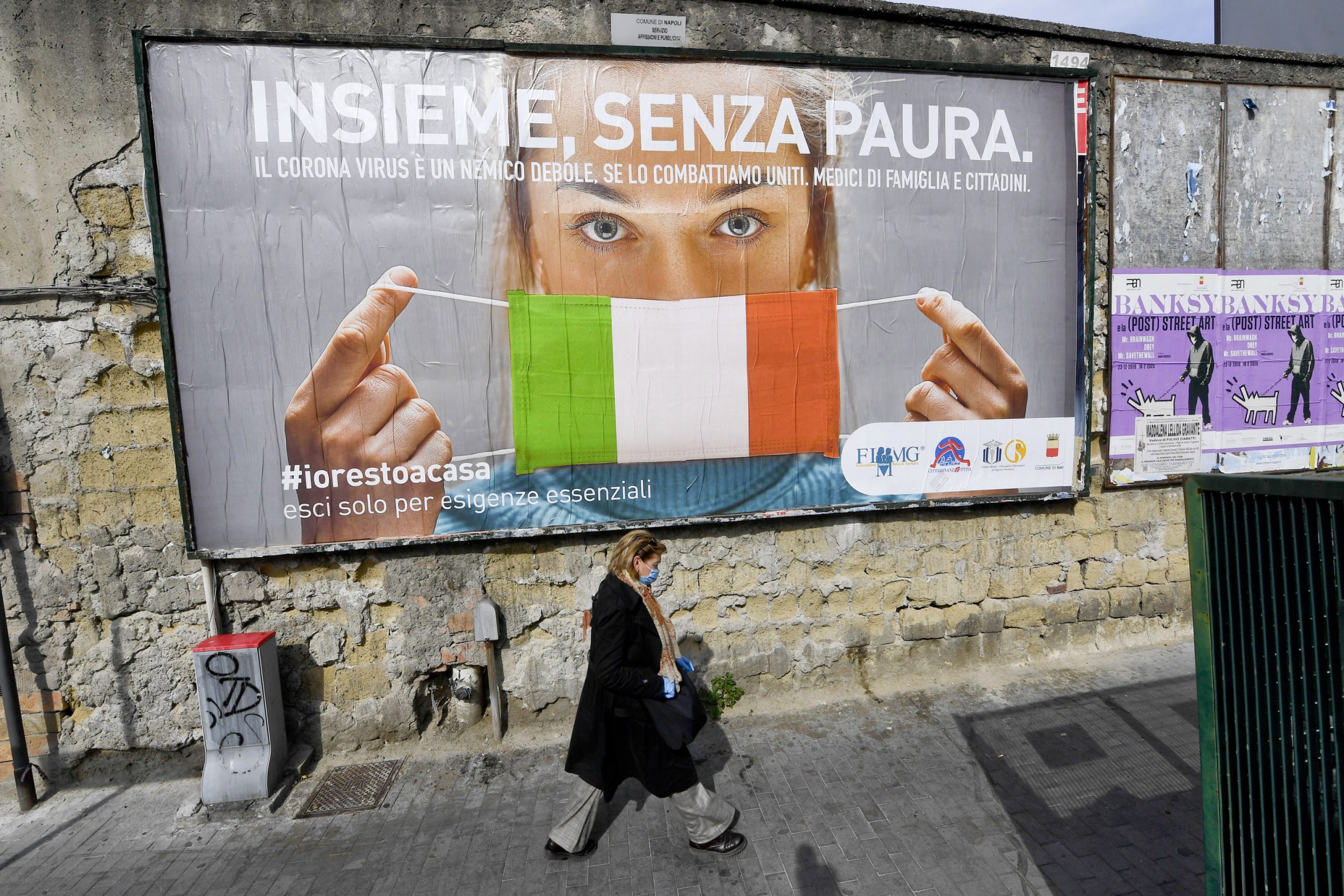 epa08311347 A woman passes a large billboard that reads in Italian 'Together, without fear' referring to the coronavirus Covid19 pandemic, in Naples, Italy, 21 March 2020. The number of deaths from the pandemic COVID-19 disease caused by the SARS CoV-2 coronavirus in Italy has now surpassed the death toll for all of China, where the outbreak originated. According to the Civil Protection agency, the total number of confirmed infections has risen to more than 47,000, while over 4,000 people have lost their lives to the disease in the Mediterranean country.  EPA/CIRO FUSCO