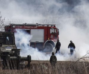 epa08275965 Greek army forces and firemen amidst tear gas used by the Turkish side at the closed-off Greek-Turkish border in Kastanies, Orestiada, Greece, 07 March 2020. Tension escalated in Kastanies, Evros, wehre migrants try to enter the EU, with the use of smoke grenades that created a heavy pall of smoke over the horizon along the fence.  EPA/DIMITRIS TOSIDIS