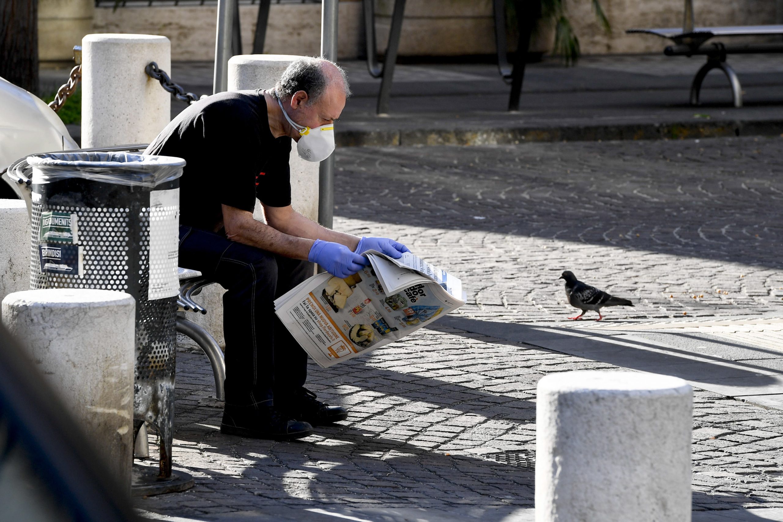 epa08349807 A man protected with a face mask and latex gloves sits on a bench and reads a newspaper in Naples, Italy, 08 April 2020, during the lockdown to stem the spread of the COVID-19 infection, caused by the novel Coronavirus.  EPA/CIRO FUSCO