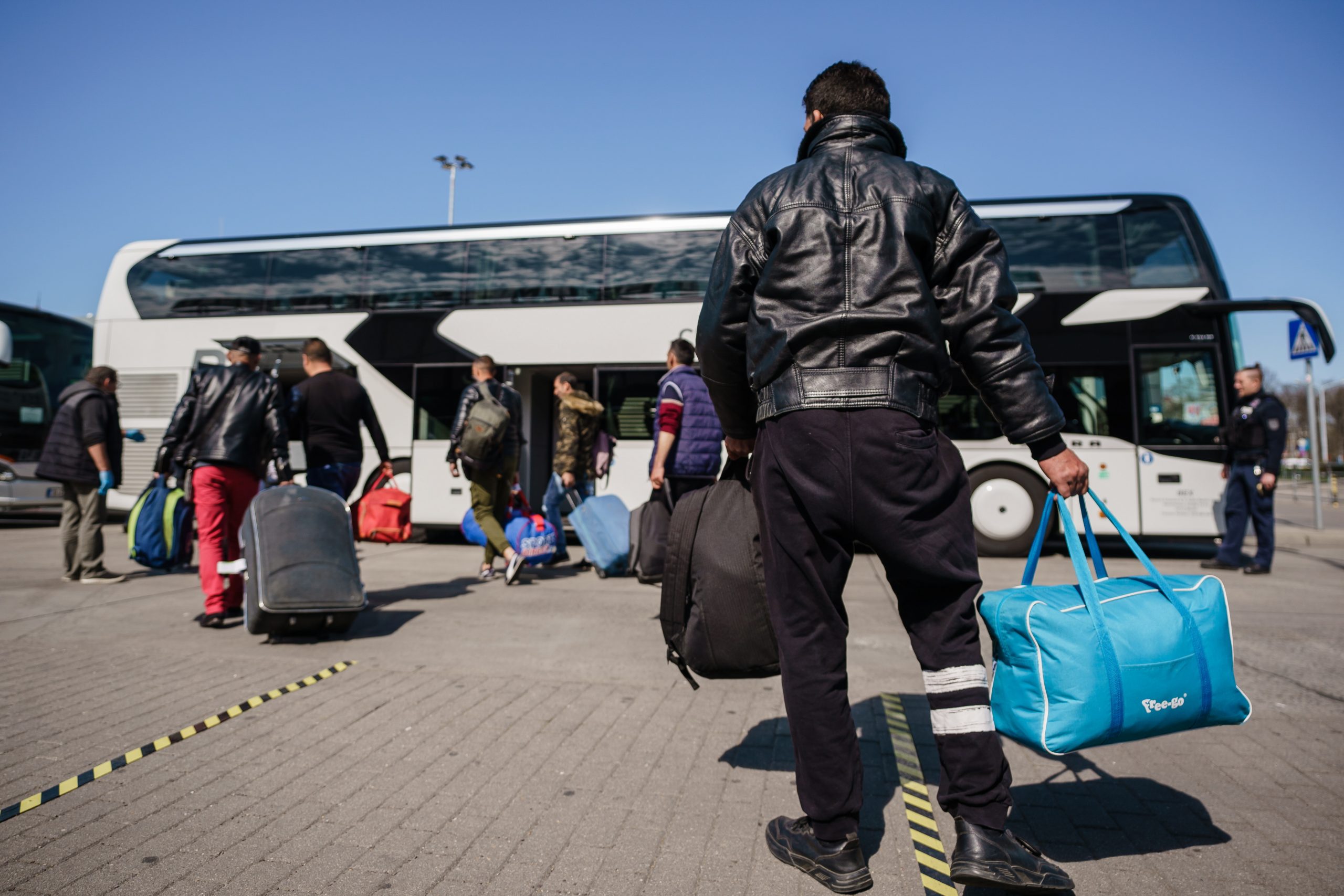 epa08352652 Seasonal harvest workers, who arrived with a charter flight from Romania, walk towards a bus, after the arrival at the Berlin-Schoenefeld airport in Schoenefeld, Germany, 09 April 2020. Due to the ongoing pandemic of the COVID-19 disease caused by the SARS-CoV-2 coronavirus and resulting closed boarders, a lack of harvest helpers appeared. Aircraft carrier Eurowings brings foreign workers to Germany, to support farmers in during the harvest of asparagus and strawberries.  EPA/CLEMENS BILAN