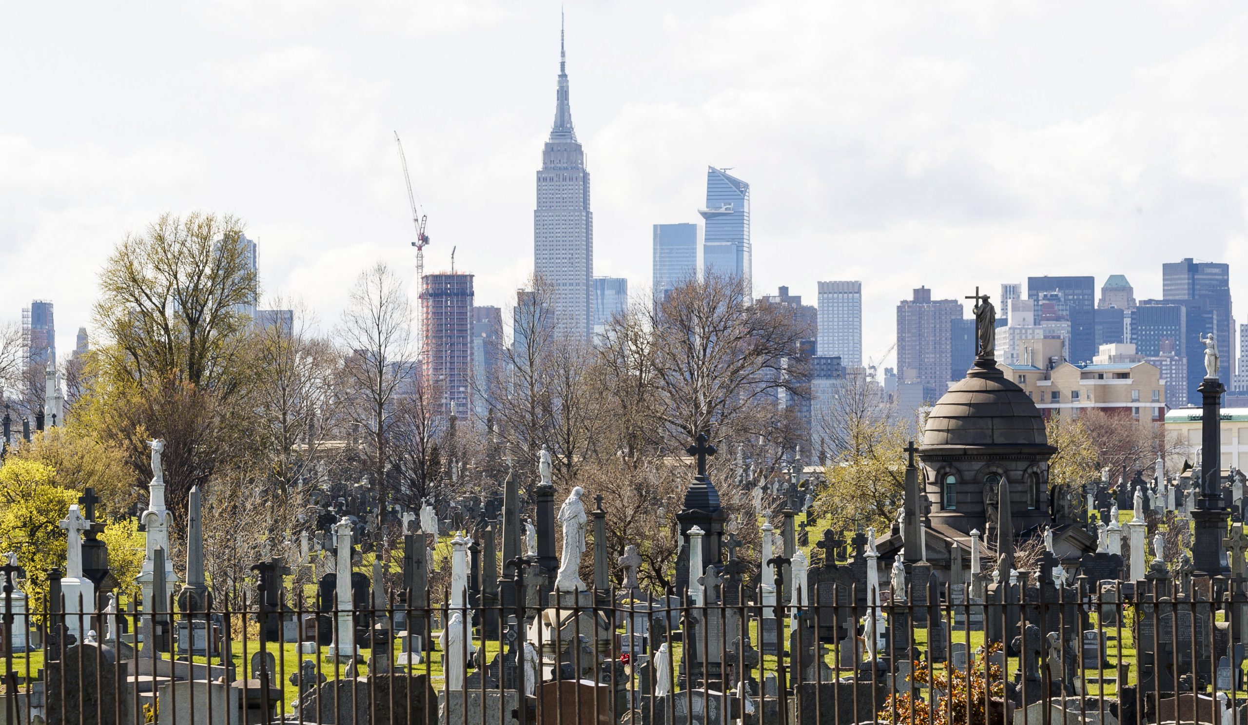 epa08354181 Gravestones and mausoleums in Calvary Cemetery in Queens are seen with the Empire State Building in the background in New York, New York, USA, on 09 April 2020. The number of patients being admitted to hospitals with COVID-19 in New York City, which is still considered to be the epicenter of the coronavirus outbreak in the United States, grew by the smallest amount in weeks but 799 people died between Wednesday and Thursday, which was another single day high for deaths.  EPA/JUSTIN LANE