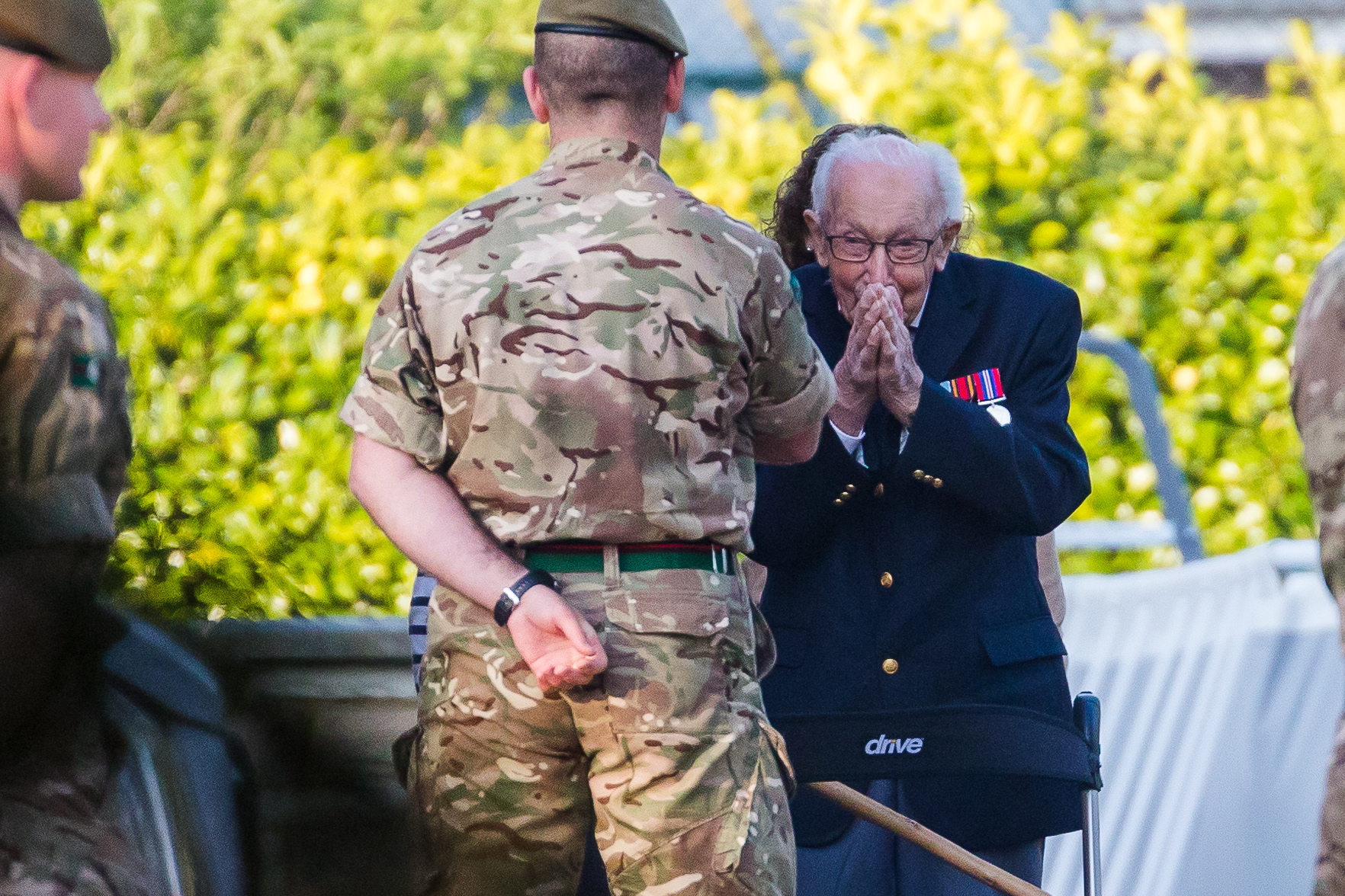 epa08365722 99-year-old British veteran Captain Tom Moore (R) reacts as he completes the 100th length of his back garden in Marston Moretaine, Bedfordshire, Britain, 16 April, 2020. Captain Tom Moore has raised over £12 million for Britain’s National Health Service (NHS) and has received donations to his fundraising challenge from around the world.  EPA/VICKIE FLORES