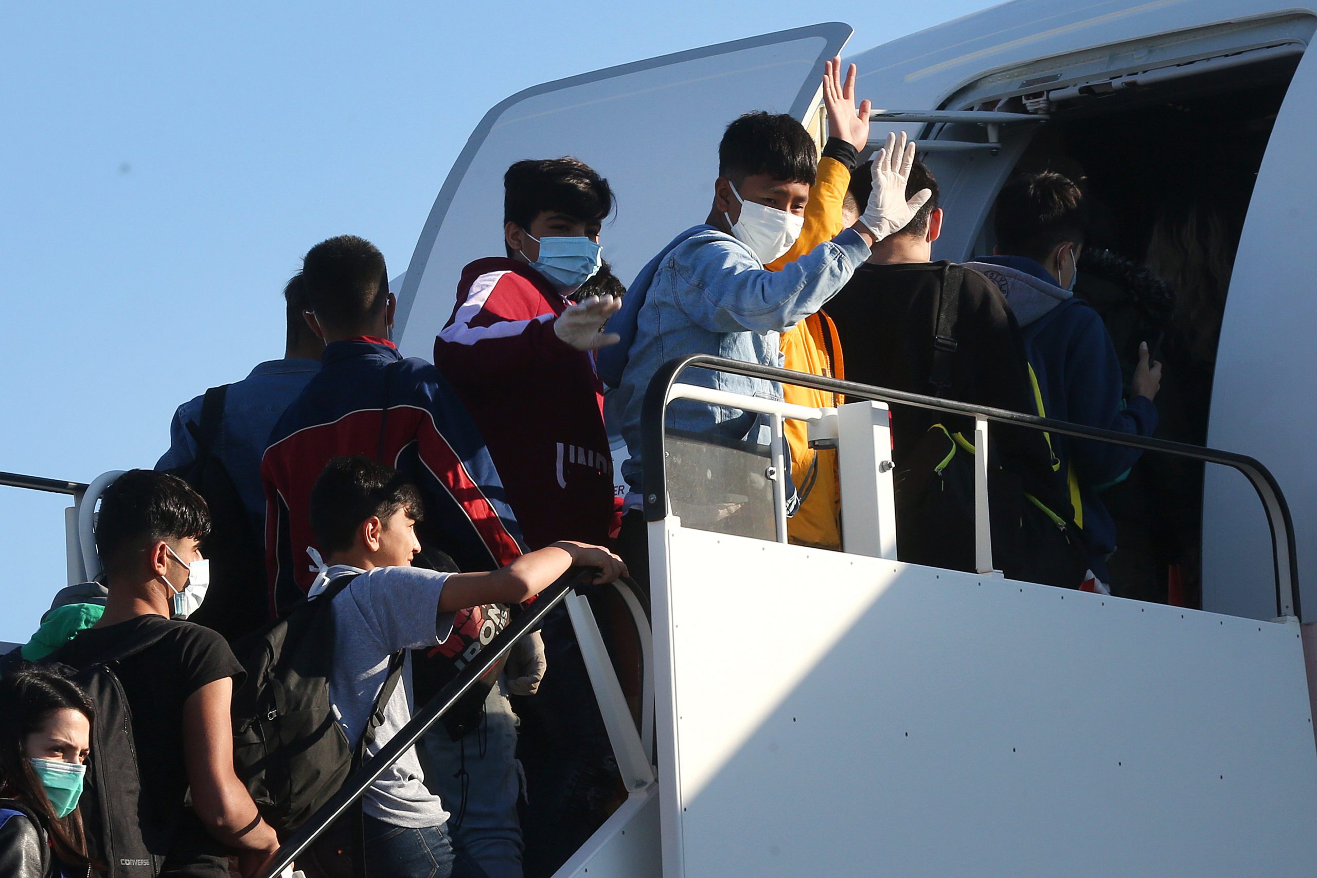 epa08370151 Unaccompanied minor refugees, who were living at the migrant camps of the islands of north Aegean Sea, board an airplane at the International Airport of Athens, to travel to Germany, in Athens, Greece, 18 April 2020. 53 children have been accepted to live in shelters for minors in Germany.  EPA/ORESTIS PANAGIOTOU