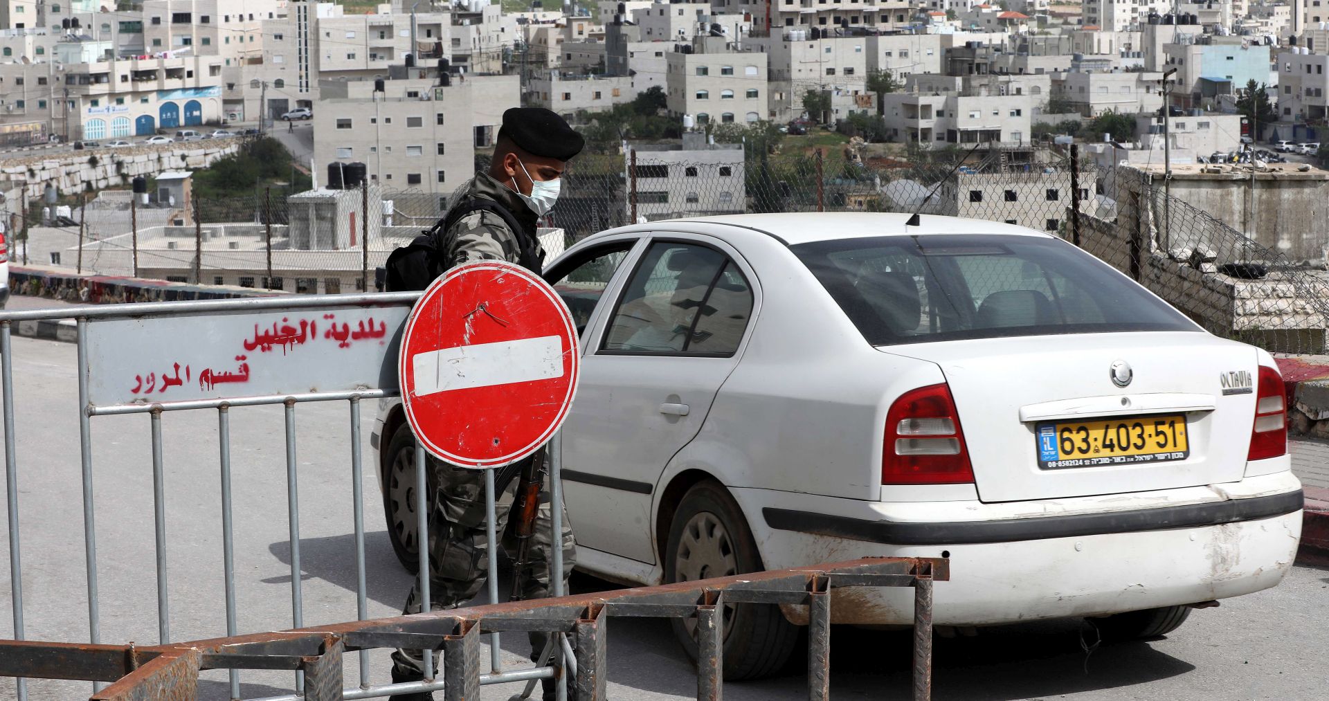 epa08371882 Palestinian security personnel opens a road at a checkpoint at an entrance to the West Bank city of Hebron, 19 April 2020. Palestinian authorities banned movement of people between cities to help stop the spread of the coronavirus which causes the Covid-19 disease.  EPA/ABED AL HASHLAMOUN