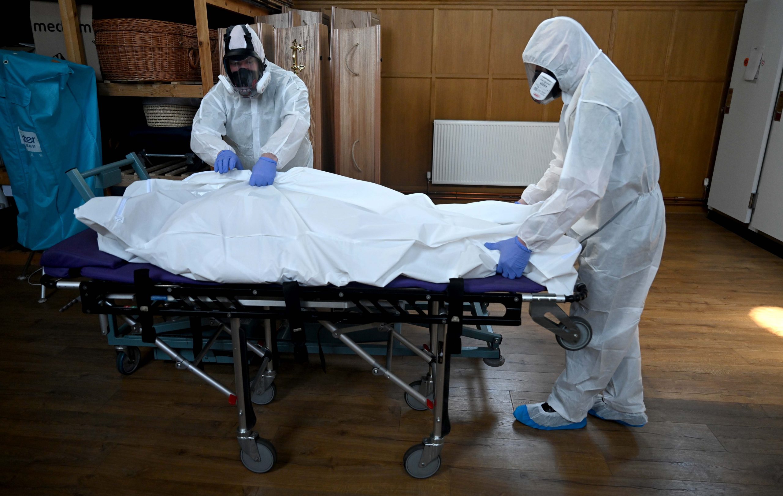 epa08382033 Mortuary workers wear protective suits as they move the body of a person who died from coronavirus at the mortuary of Poppy's Funerals in London, Britain, 24 April 2020. The SARS-CoV-2 coronavirus which causes the Covid-19 disease is having a major affect on funeral services, according to Funeral Director Poppy Mardall who runs Poppy's Funeral's in south London. She says: 'We are much busier with 20-30 percent more people being brought in which is a strain. When handling bodies which have had COVID-19, we must wear protective suits, high grade masks and gloves. All funerals are heavily restricted to around 10 people. People can see the body but can no longer have contact. We are seeing more funerals being streamed online and memorials put to a later date. Instead of flowers, children are drawing them. It is harder for people to do the normal rituals associated with death. It is important to remember than people have died and not treat them like a statistic. Funeral directors are helping people pick up the pieces and sudden death means more trauma.'  EPA/NEIL HALL  ATTENTION: This Image is part of a PHOTO SET