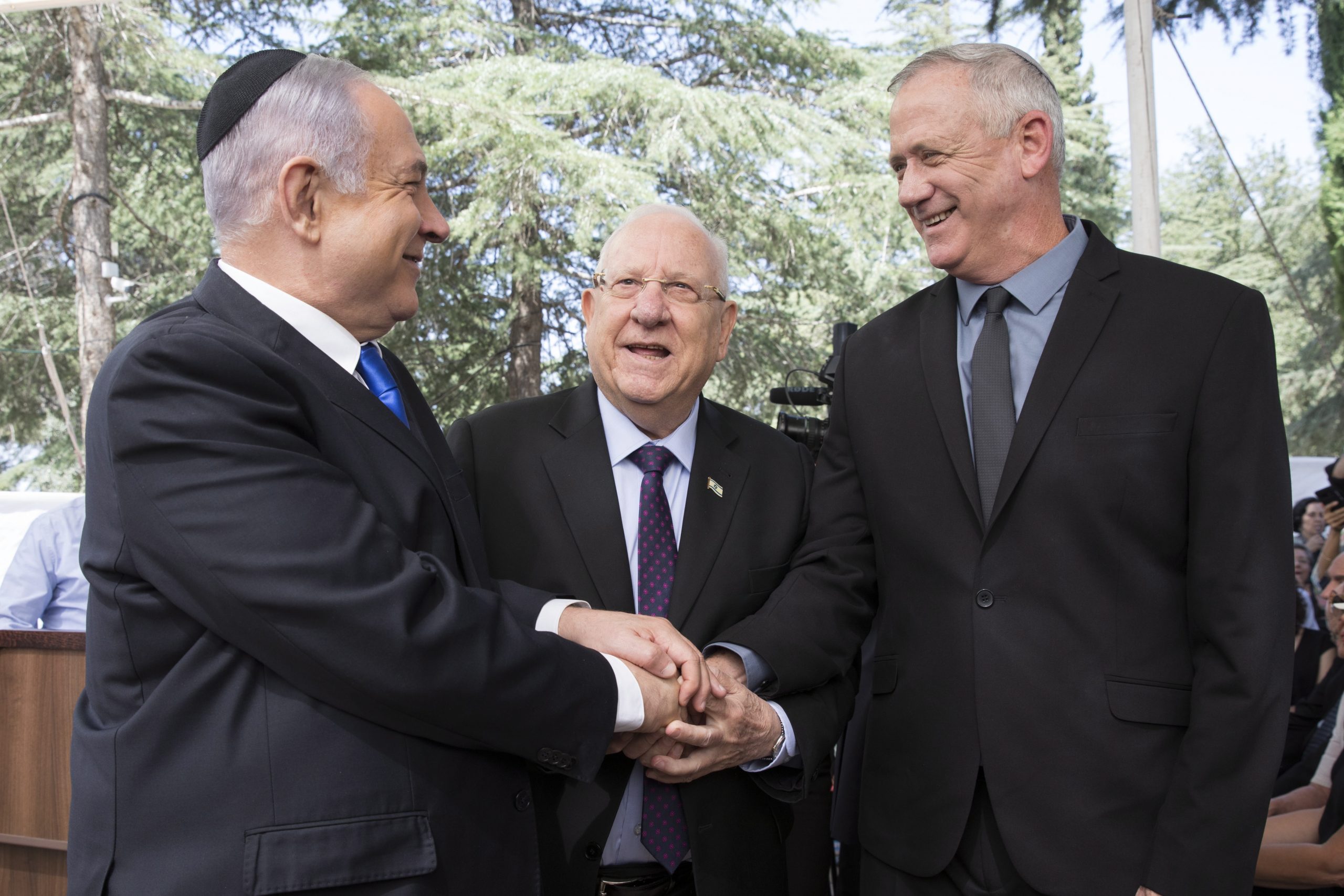 epa08373681 (FILE) -  Israeli Prime Minister Benjamin Netanyahu (L), Israeli President Reuven Rivlin (C) and Benny Gantz, former Israeli Army Chief of Staff and chairman of the Blue and White Israeli centrist political alliance (R) join hands as they attend a memorial service for late Israeli president Shimon Peres at Mount Herzl in Jerusalem, 19 September 2019(issued 04 April 2020). Media report that Netanyahu  and Gantz agreed to sign a coalition deal to form a government after three elections and to rotate the premiership.  EPA/ABIR SULTAN