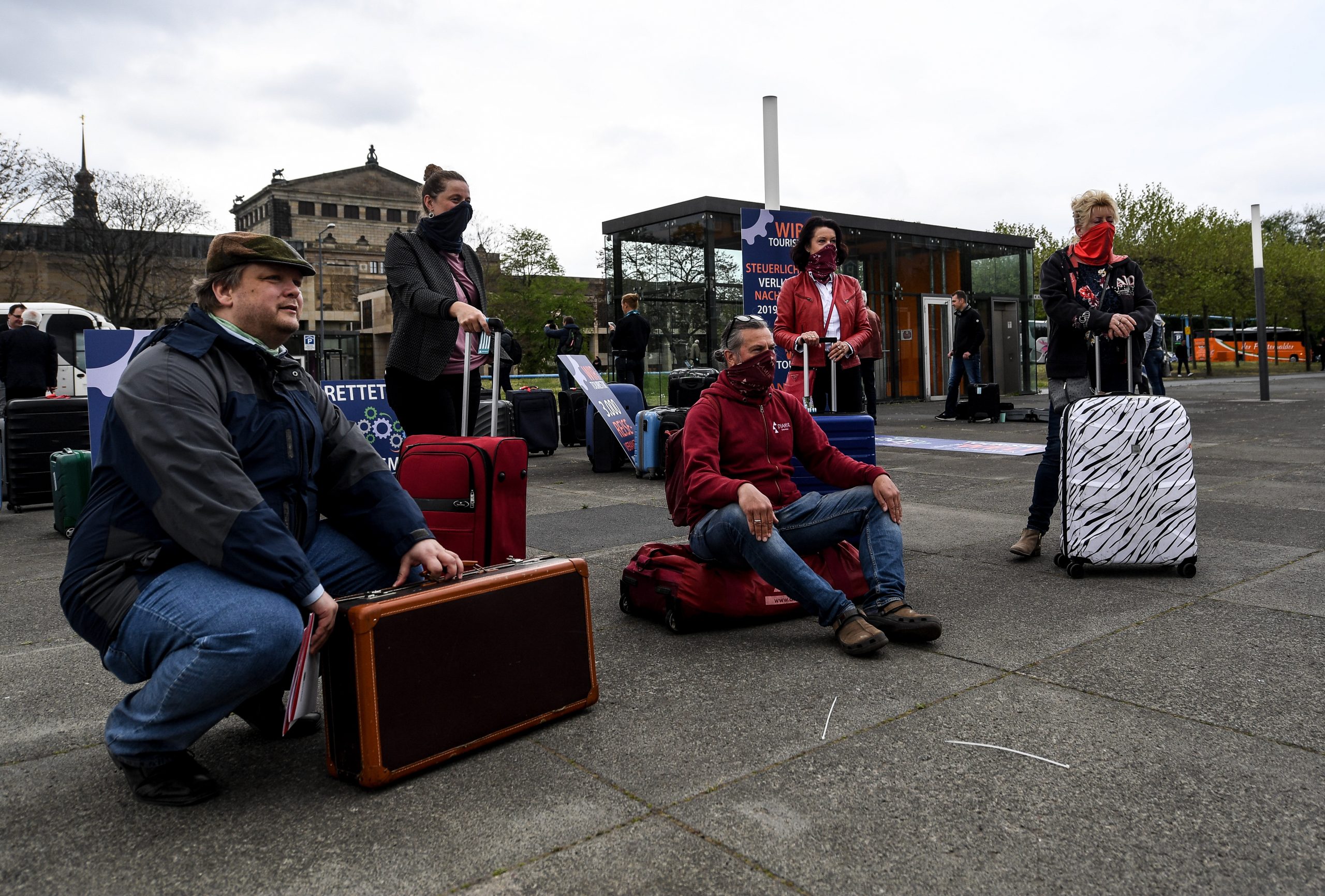 epa08391015 Protesters sit on luggage during a demonstration of travel agencies employees in Dresden, Germany, 29 April 2020. Some of Saxony's travel agencies workers blocked Dresden streets with tour buses to draw attention to the difficult economic situation of the tourism industry during the coronavirus pandemic.  EPA/FILIP SINGER