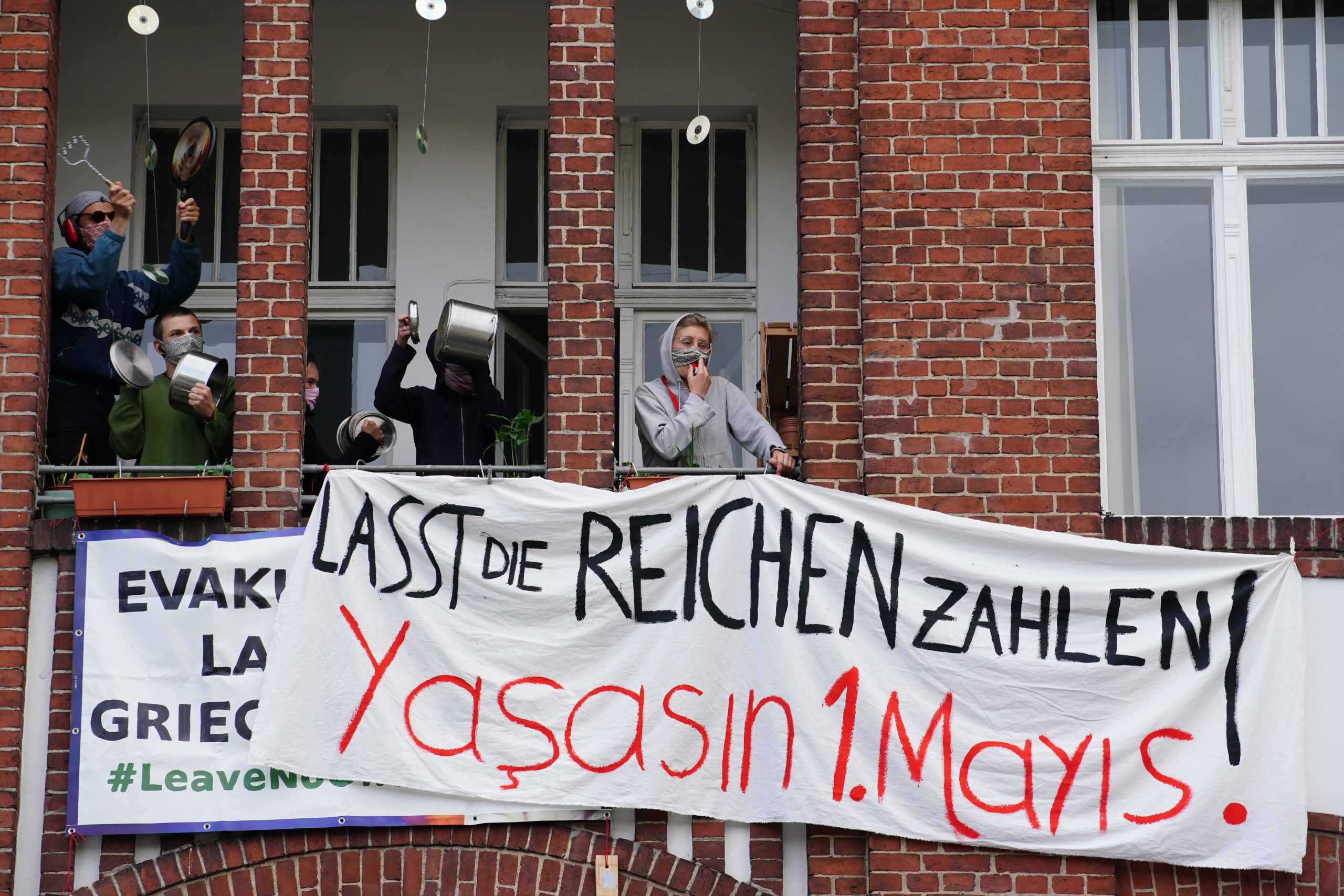 epa08393798 Demonstrators on a balcony wear protective masks holding banners reading 'Let the rich pay' during a protest in the Berlin district Wedding in Berlin, Germany, 30 April 2020. On the eve of the feast day of Saint Walpurga, in German tradition witches are believed to hold an annual meeting in a range of wooded hills in central Germany as they await the arrival of spring. In the late 19th century, May Day was chosen as the date for International Workers' Day with rallies and demonstrations up until now. This year, May Day takes place under the influence of the pandemic crisis of the SARS-CoV-2 coronavirus which causes the Covid-19 disease.  EPA/CLEMENS BILAN