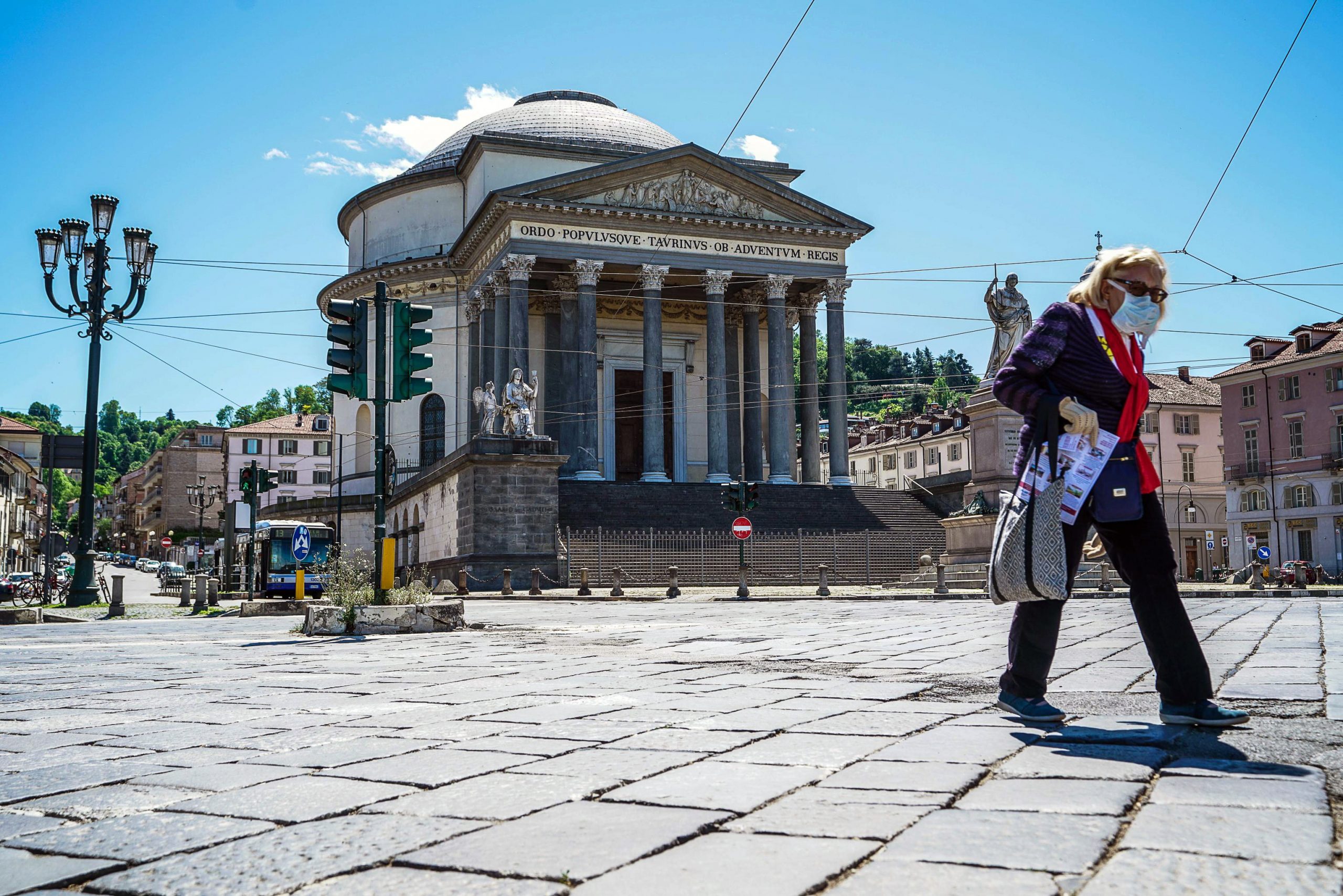 epa08398756 A woman wearing a protective face mask walks in front of the church of Gran Madre di Dio in Turin, Italy, 03 May 2020, amid the ongoing coronavirus COVID-19 pandemic. Countries around the world are taking measures to stem the widespread of the SARS-CoV-2 coronavirus which causes the COVID-19 disease.  EPA/TINO ROMANO