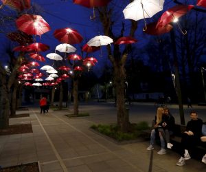epa08403754 People sit under an umbrellas installation in the colors of the national flag, in Ogre, Latvia, 05 May 2020, during the coronavirus pandemic.  EPA/TOMS KALNINS