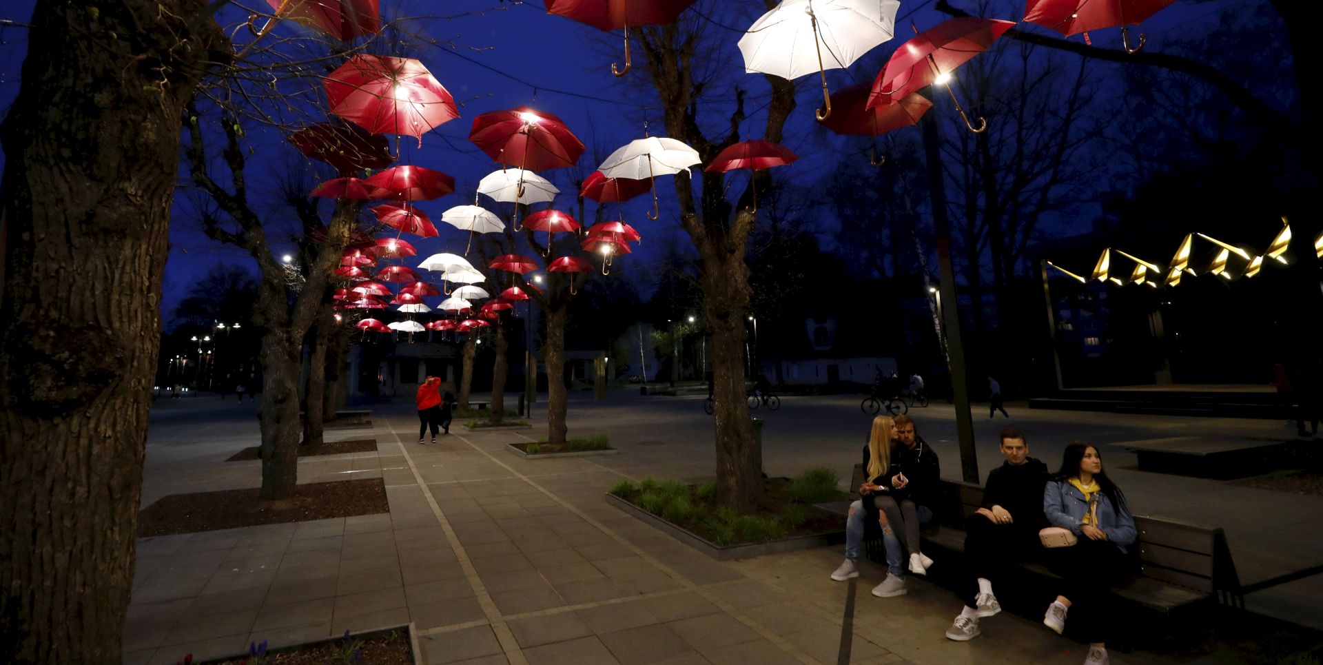 epa08403754 People sit under an umbrellas installation in the colors of the national flag, in Ogre, Latvia, 05 May 2020, during the coronavirus pandemic.  EPA/TOMS KALNINS