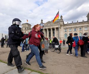 epa08426198 German police officers detain a protester during a demonstration in front of the Reichstag building, seat of the German parliament the Bundestag in Berlin, Germany, 16 May 2020. A series of demonstrations are held throughout Germany, calling for ending of the social and economical restrictions imposed due to the coronavirus pandemic. The events are organized by groups of various motives, right wing activists, conspiracy theory believers and more.  EPA/OMER MESSINGER