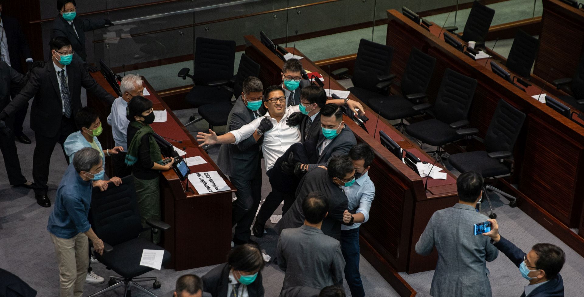 epa08428888 Pro-democracy lawmaker Lam Cheung-ting (top-C, in white shirt), is carried out of the chamber by security guards during a scuffle with pro-Beijing lawmakers at a the Legislative Council meeting in Hong Kong, China, 18 May 2020. Several pro-democracy legislators were dragged out of the chamber by security guards as the two camps tussled for control of the House Committee which has been gridlocked for months. The pro-establishment camp called the vote, after most of the pan-democratic lawmakers had been dragged out of the room by security guards after the meeting descended into utter chaos.  EPA/JEROME FAVRE