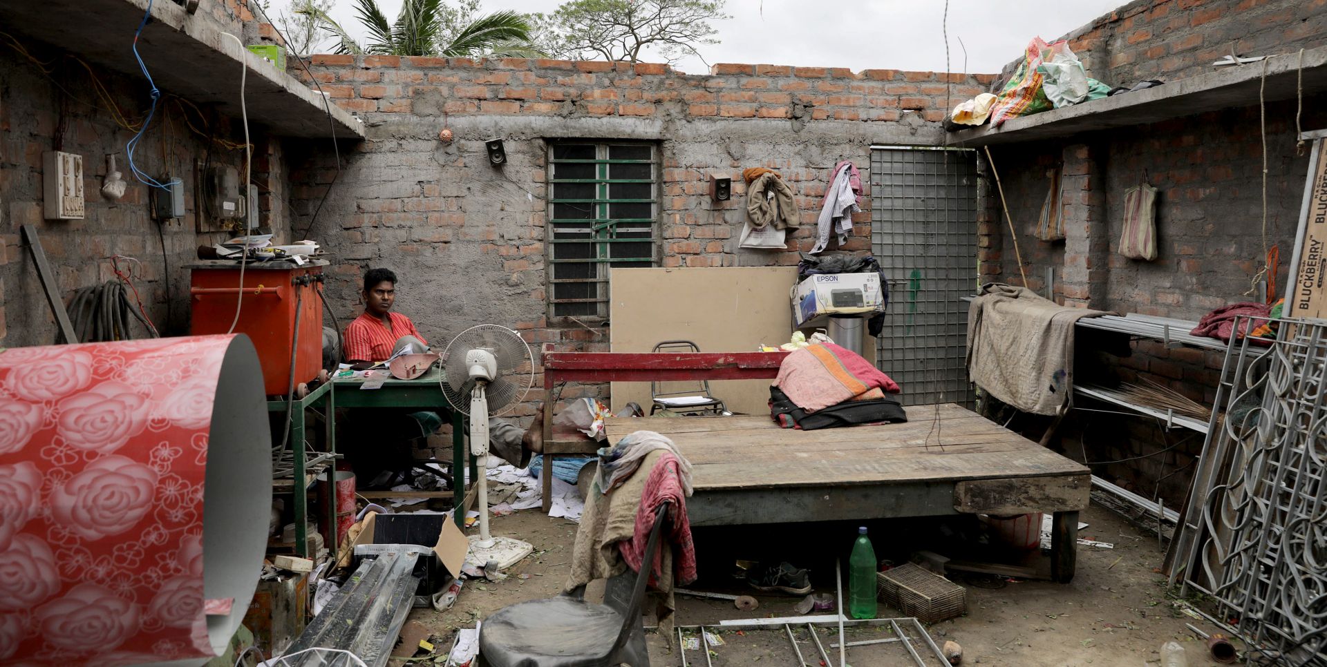 epa08435246 A cyclone victim sits in his house without a roof after Cyclone Amphan made landfall, in Bokkhali village near the Bay of Bengal, India, 21 May 2020. The Odisha government and Bengal government are considering a mass evacuation of the area.  EPA/PIYAL ADHIKARY
