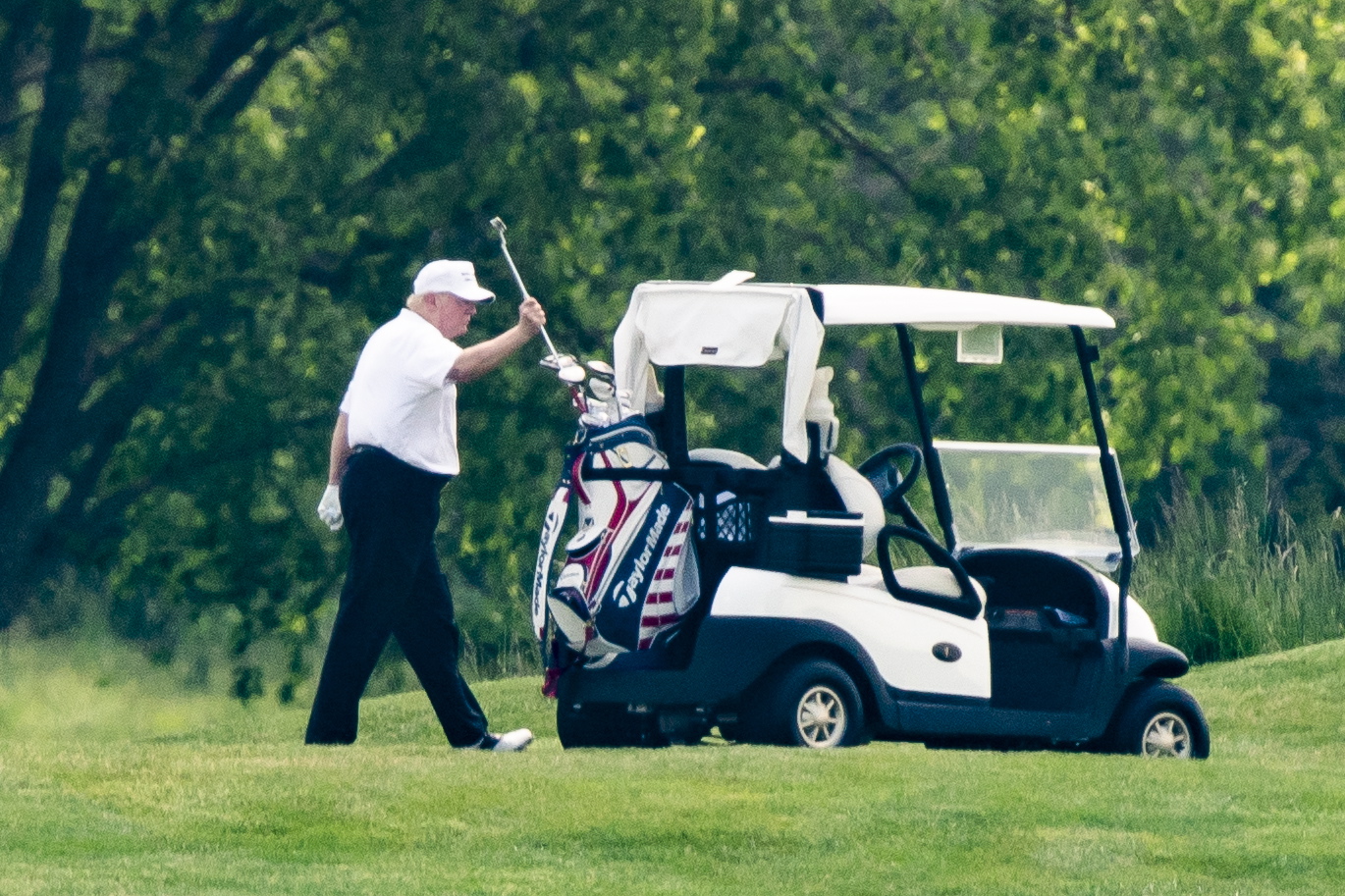 epa08440052 US President Donald J. Trump, wearing a white hat and white Polo shirt, plays golf at the Trump National Golf Club in Sterling, Virginia, USA, 23 May 2020. It is the first time the president has played golf since the lockdown over the coronavirus COVID-19 pandemic.  EPA/JIM LO SCALZO
