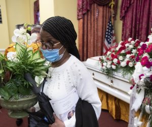 epa08450673 Lavoris Moore carries flowers beside the casket holding the remains of her sister, Evelyn Moore Smith, who died with coronavirus COVID-19 disease, following a funeral service at Ronald Taylor II Funeral Home in Washington, DC, USA, 28 May 2020. Evelyn Moore Smith was married for forty-five years to Calvin Smith Sr. and passed away 20 May, 2020, at the age of sixty-eight. The official COVID-19 death toll in the US has passed one hundred thousand, which is more than any other nation.  EPA/MICHAEL REYNOLDS  ATTENTION: This Image is part of a PHOTO SET