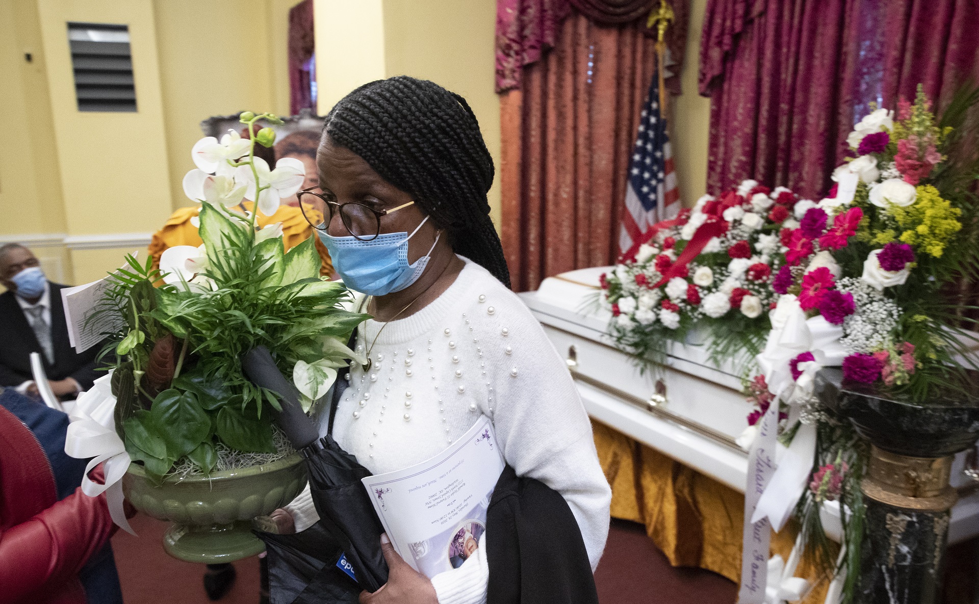 epa08450673 Lavoris Moore carries flowers beside the casket holding the remains of her sister, Evelyn Moore Smith, who died with coronavirus COVID-19 disease, following a funeral service at Ronald Taylor II Funeral Home in Washington, DC, USA, 28 May 2020. Evelyn Moore Smith was married for forty-five years to Calvin Smith Sr. and passed away 20 May, 2020, at the age of sixty-eight. The official COVID-19 death toll in the US has passed one hundred thousand, which is more than any other nation.  EPA/MICHAEL REYNOLDS  ATTENTION: This Image is part of a PHOTO SET