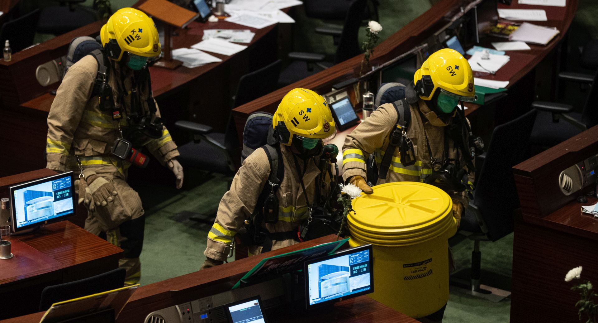 epa08464147 Firefighters carry a container filled with a foul-smelling object thrown by pan-democrat lawmakers during the third reading of the National Anthem bill at the Legislative Council in Hong Kong, China, 04 June 2020. Under the bill, anyone convicted of misusing or insulting the 'March of the Volunteers', the national anthem of the People's Republic of China, could face a fine of up to 50,000 Hong Kong dollars (6,449 US dollars) and three years in jail.  EPA/JEROME FAVRE