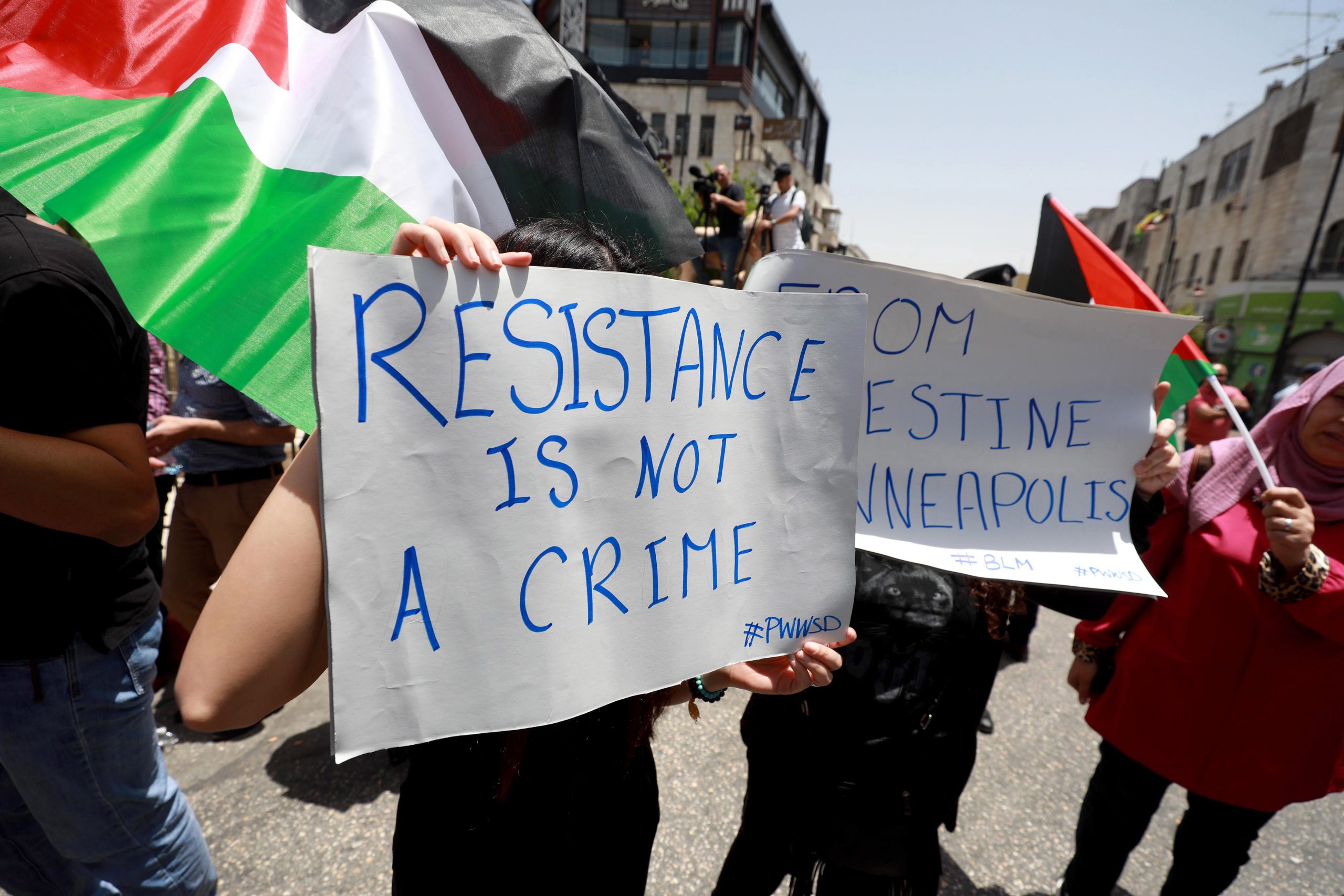 epa08472774 Palestinian protesters hold placards during a protest against Israel's plans to annex parts of West Bank, and in solidarity with the US protesters over the death George Floyd, in the West Bank town of Ramallah, 08 June 2020.  EPA/STR