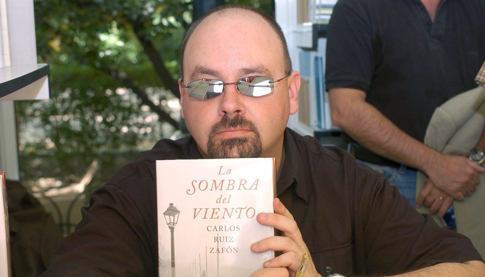 epa08495283 (FILE) - Spanish author Carlos Ruiz Zafon poses for a photograph while holding up a copy of his bestselling novel during a book-signing event at the Madrid Book Fair in Madrid, Spain, 28 May 2005 (reissued 19 June 2020). Zafon passed away at the age of 55 in Los Angeles, USA, after a long struggle against colon cancer, according to a press release by the publishing house Planeta, which worked extensively with the Spanish novelist over two decades of prolific partnership. The author of bestsellers such as 'The Shadow of the Wind' (2001) and 'The Labyrinth of Spirits' (2016) had been a resident of LA since 1993. Born in Barcelona in 1964, Zafon got by as a publicist and screenwriter before earning literary fame and critical acclaim for 'The Shadow of the Wind,' a Gothic-style mystery page-turner that has sold dozens of millions of copies worldwide, making it one of the most successful fiction books of all time in terms of sales.  EPA/VICTOR LERENA *** Local Caption *** 53318763