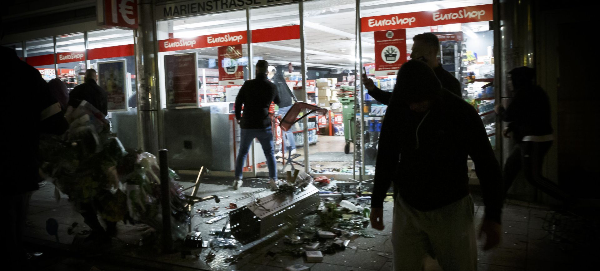 dpatop - 21 June 2020, Baden-Wuerttemberg, Stuttgart: People stand in front of a looted shop in Marien street after several people rioted in downtown Stuttgart during night. Photo: Julian Rettig/dpa