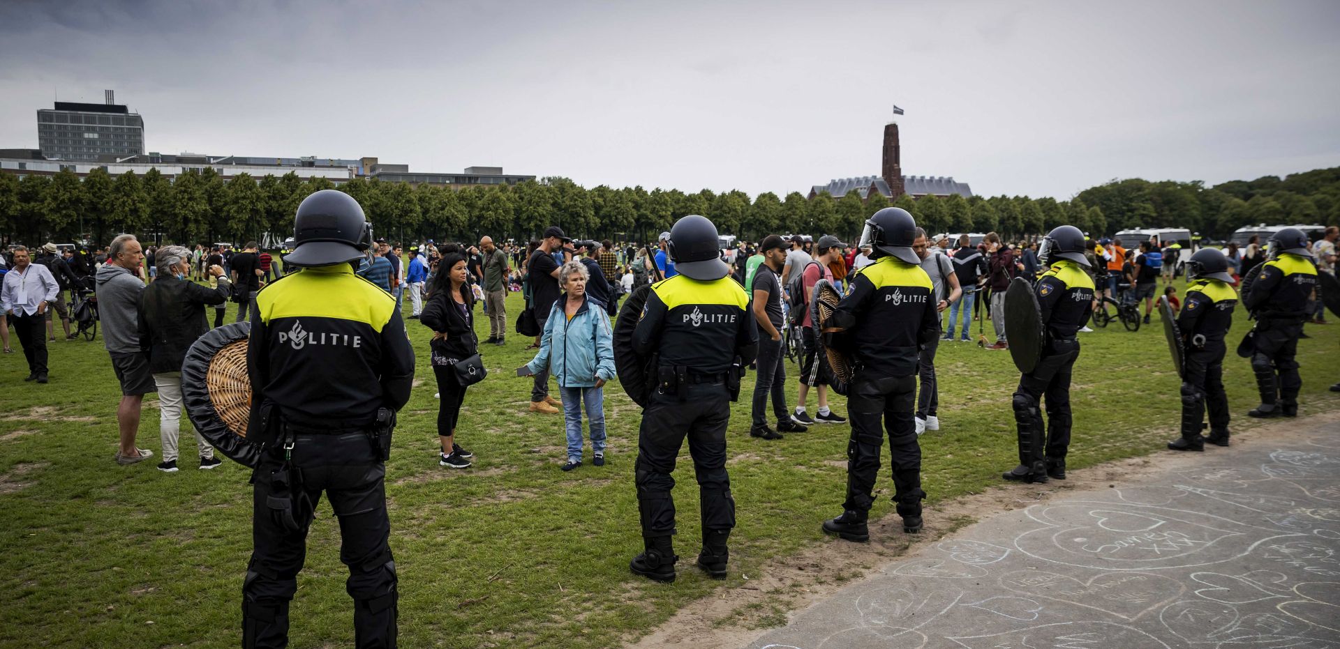 epa08500783 Police watch protesters in the center of The Hague, Netherlands, 21 June 2020. Demonstrators attended the protest on event venue Malieveld that focused on the coronavirus measures of the cabinet. The protest was initially banned due to an excessive number of interested people, but Mayor Remkes eventually allowed a short gathering.  EPA/ROBIN VAN LONKHUIJSEN