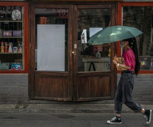 epa08507475 A woman walks past a closed shop in Nanluoguxiang alley, a famous tourist spot in the Hutong neighborhood, amid a new coronavirus outbreak in Beijing, China, 23 June 2020 (issued 25 June 2020). Almost 2.3 million people were tested for COVID-19 since 13 June according to the municipal government.  EPA/ROMAN PILIPEY