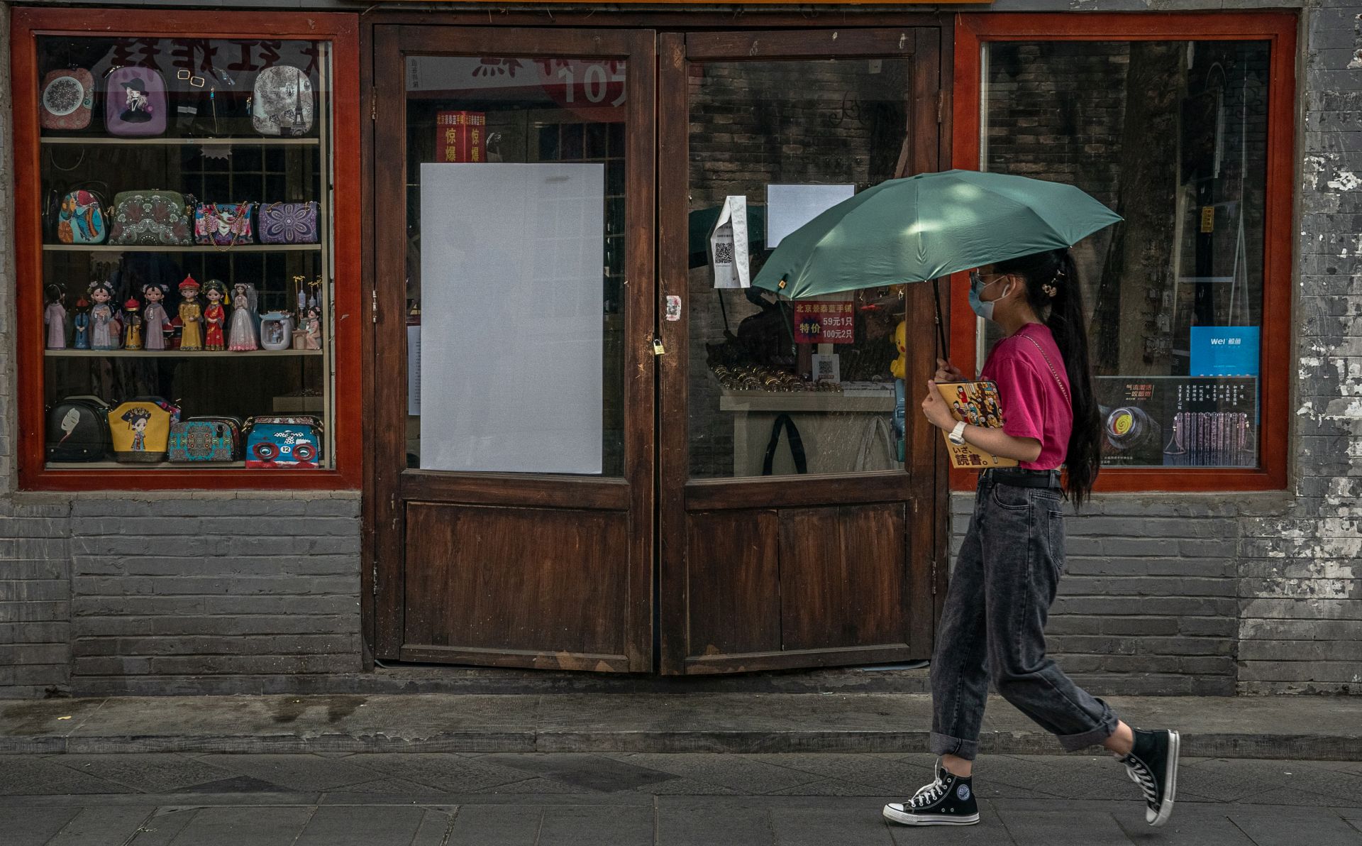 epa08507475 A woman walks past a closed shop in Nanluoguxiang alley, a famous tourist spot in the Hutong neighborhood, amid a new coronavirus outbreak in Beijing, China, 23 June 2020 (issued 25 June 2020). Almost 2.3 million people were tested for COVID-19 since 13 June according to the municipal government.  EPA/ROMAN PILIPEY