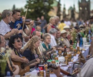 epa08518693 Musicians perform as diners sit at a gigantic table measuring 515 meters (1,690 feet) in length and spanning the entirety of the iconic Charles Bridge in Prague, Czech Republic, 30 June 2020. The massive dinner party came after an easing of the restrictions imposed in a bid to slow down the spread of the pandemic COVID-19 disease caused by the SARS-CoV-2 coronavirus. The event's organizers covered the colossal table with a white tablecloth and adorned it with flowers. Attendees were encouraged to bring their own food and share it with others. The still-low number of foreign visitors to the Czech Republic due to the coronavirus pandemic also provided an opportunity for locals to enjoy one of their city's most famous landmarks without the habitual hubbub from the throngs of tourists that usually crowd the picturesque capital.  EPA/MARTIN DIVISEK