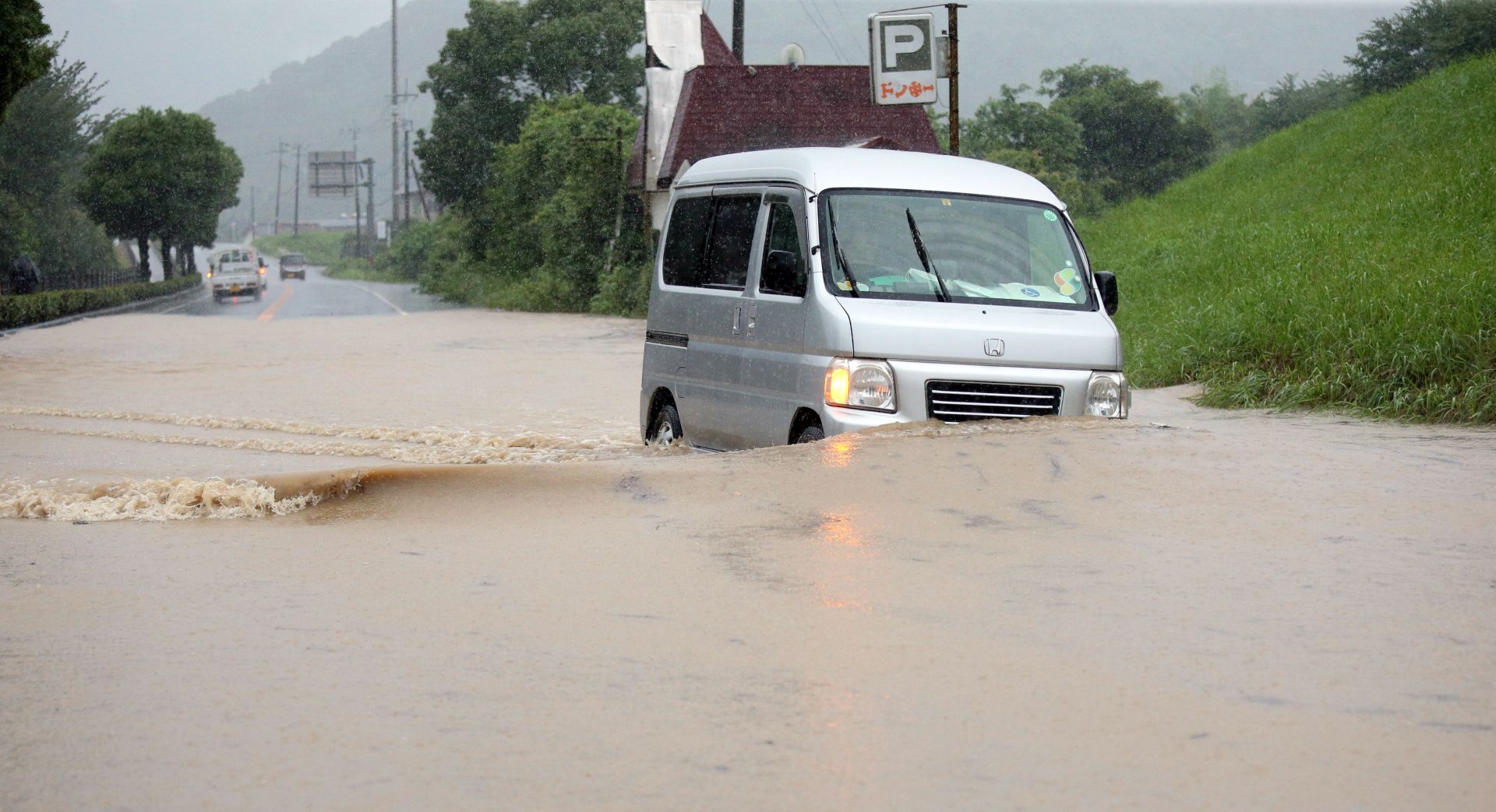 epa08525871 A minivan drives through a flooded street in Yatsushiro, Kumamoto prefecture, southwestern Japan, 04 July 2020. Local authorities asked the evacuation of more than 76,000 residents in Japan's southwestern prefectures of Kumamoto and Kagoshima following floods and mudslides triggered by torrential rain.  EPA/JIJI PRESS JAPAN OUT EDITORIAL USE ONLY/  NO ARCHIVES