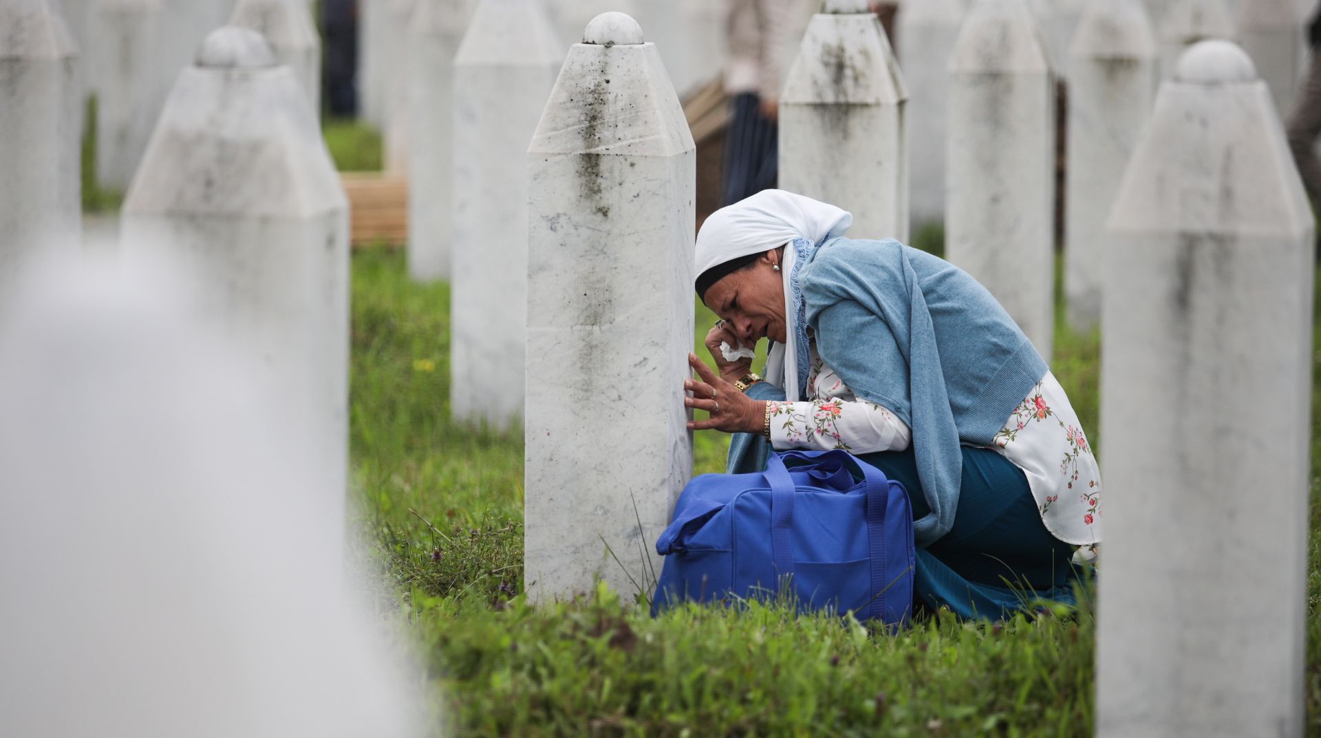 epa08529982 (FILE) - A mourning woman sits between gravestones on the Potocari Memorial Center in Srebrenica, Bosnia and Herzegovina, 11 July 2018 (reissued 06 July 2020). A group of 35 victims of the war crime massacre were transferred from the  town of Visoko to be buried on the city's Potocari Memorial Center on the occasion of the 23rd anniversary of the massacre. A quarter of a century ago, the world witnessed the worst mass murder on European soil since World War II. Some 7,000-8,000 Bosniaks were slaughtered and 20,000 civilians were forcibly displaced in an act of ethnic cleansing perpetrated in the small eastern Bosnian village of Srebrenica, whose name will forever be linked to the infamous 1995 massacre. Today, 25 years after the massacre, the memory of its victims is kept alive by several institutions, such as the Museum of Crimes Against Humanity and Genocide in Sarajevo or a permanent exhibit at the 'Memorial Center Srebrenica-Potocari' that now occupies the former headquarters of the Dutch UNPROFOR Battalion.  EPA/JASMIN BRUTUS  ATTENTION: This Image is part of a PHOTO SET