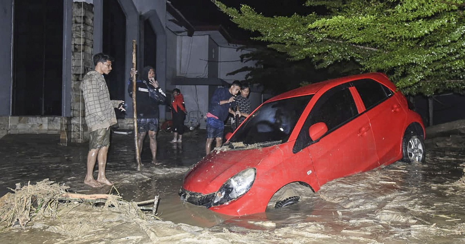 epa08545089 People inspect a damage car after it was hit by flash floods in Mssamba, Luwu Utara, South Sulawesi, Indonesia, 14 July 2020. According to Indonesian National Board for Disaster Management (BNPB), at least 10 people are dead and dozens of others missing.  EPA/STR