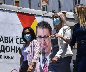 epa08545398 People wearing protective masks walk in front of the electoral billboard of the leader of the opposition VMRO DPMNE, Hristijan Mickovski in Skopje, Republic of North Macedonia, 14 July 2020. The Balkan nation conducts three days of early general elections voting in the middle of the Covid-19 pandemic. Infected persons and the quarantined citizens are voting on 13 July, while prisoners and the elders on 14 July, before general voting takes place on 15 July.  EPA/GEORGI LICOVSKI