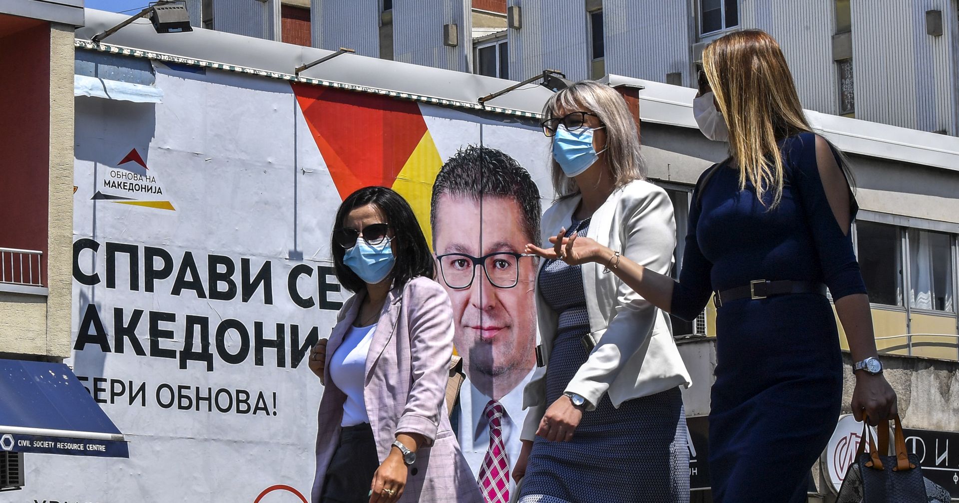 epa08545398 People wearing protective masks walk in front of the electoral billboard of the leader of the opposition VMRO DPMNE, Hristijan Mickovski in Skopje, Republic of North Macedonia, 14 July 2020. The Balkan nation conducts three days of early general elections voting in the middle of the Covid-19 pandemic. Infected persons and the quarantined citizens are voting on 13 July, while prisoners and the elders on 14 July, before general voting takes place on 15 July.  EPA/GEORGI LICOVSKI
