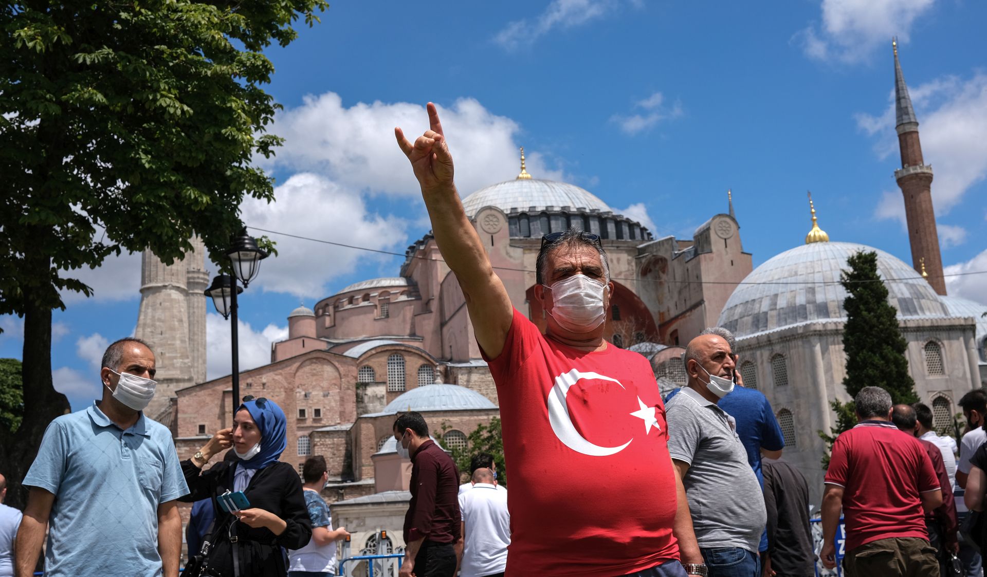 epa08551728 A Turkish nationalist flashes a grey wolf sign which is the symbol of Turkish Nationalists in front of the Hagia Sophia as Turkish people continue to celebrate Turkey's decision that the 1,500 year old UNESCO World Heritage site Hagia Sophia can be converted into a mosque, in Istanbul, Turkey, 17 July 2020. Turkey's highest administration court on 10 July 2020 ruled that the museum that was once a mosque built in a Cathedral can be turned into a mosque again by annulling its status as museum. Hagia Sophia will open on 24 July 2020 as a mosque and Turkish President Recep Tayyip Erdogan will attend first Friday pray.  EPA/SEDAT SUNA